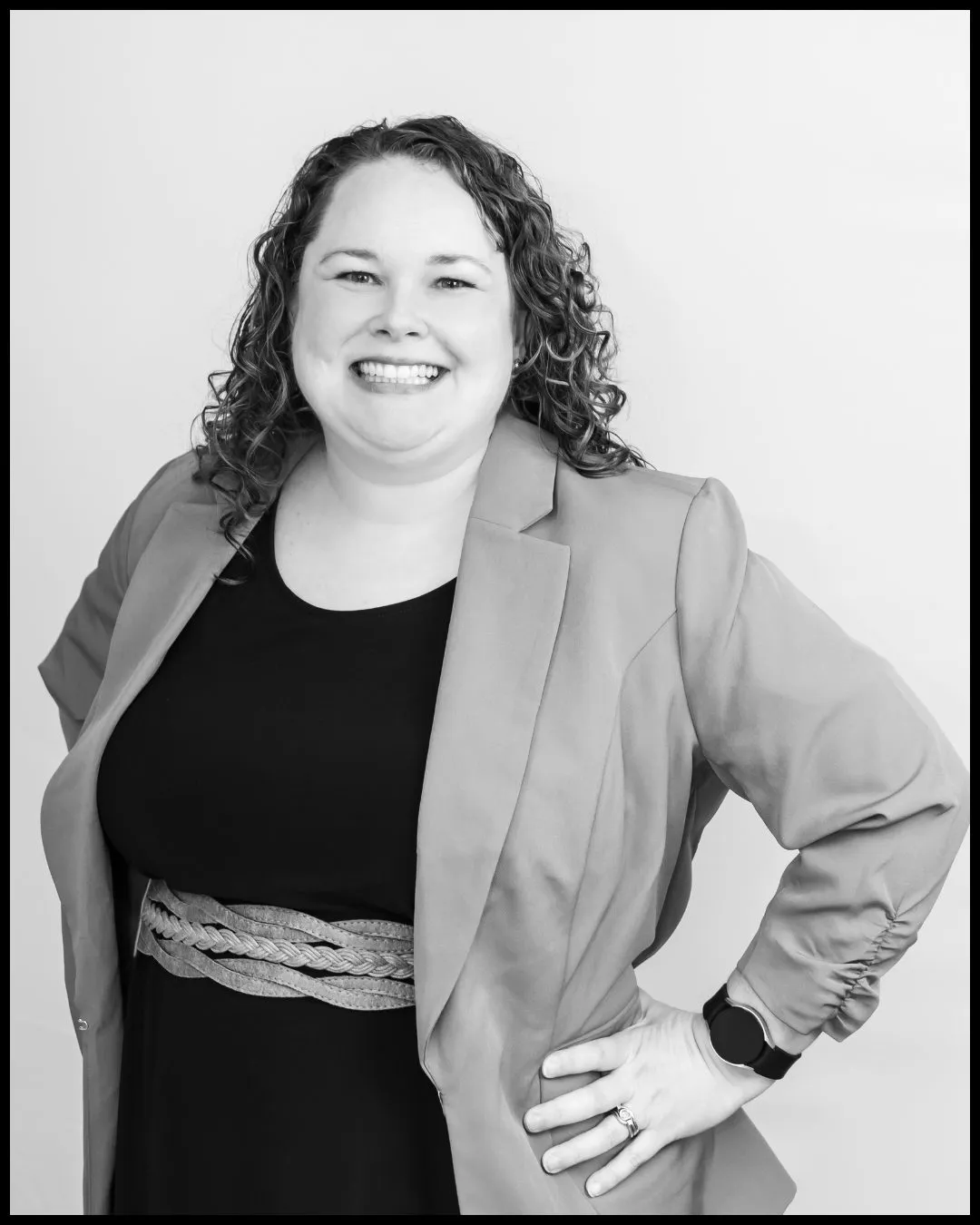 Alexa Blackwell in a light blazer over a black dress with a braided belt, photographed in black and white