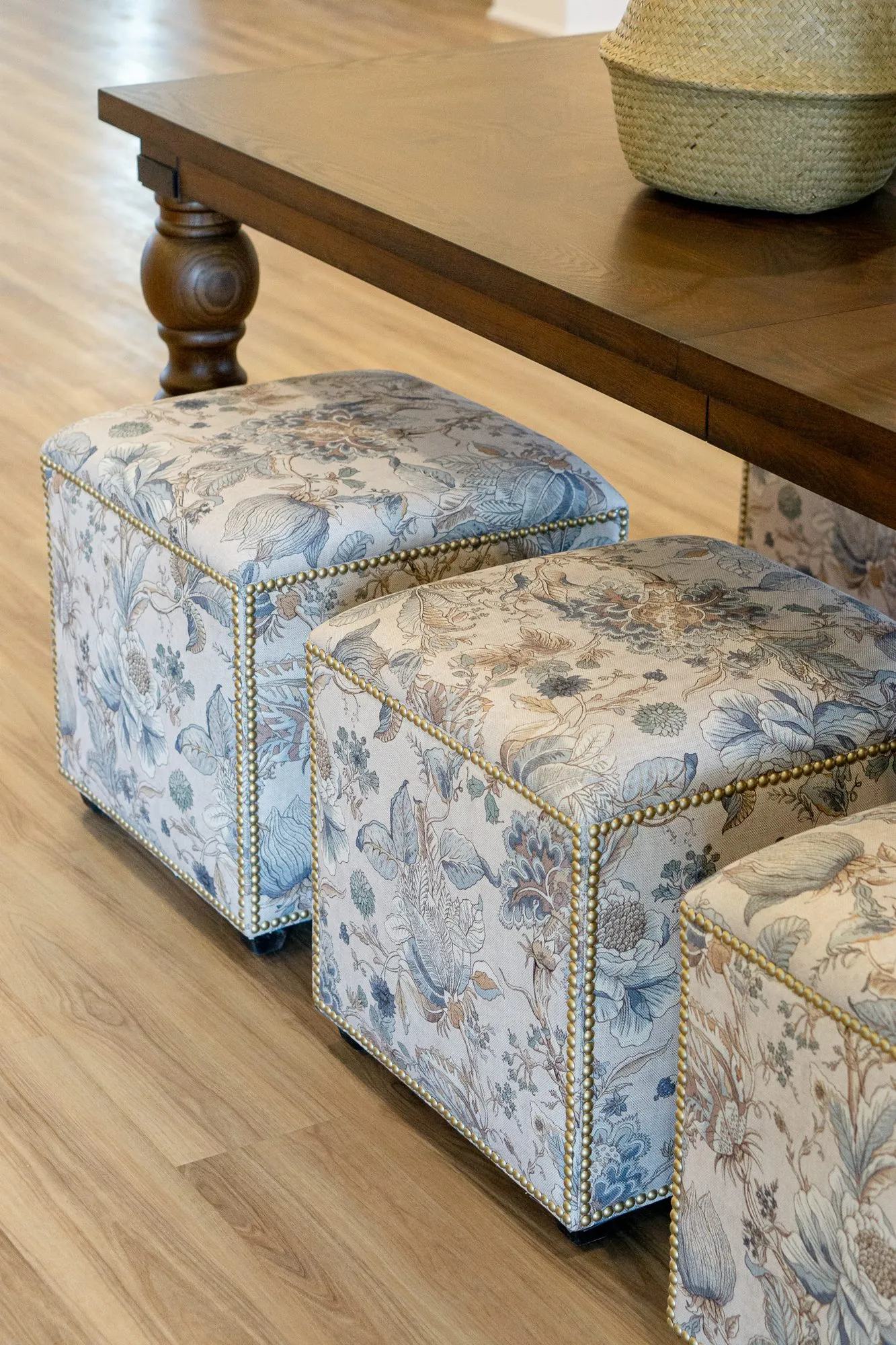 Senior living interior detail: blue and cream floral cube ottomans with nailhead trim under a walnut table