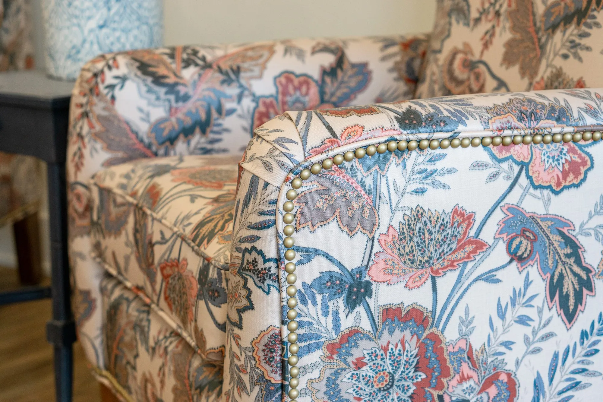 Senior living interior detail: floral print wing chair with brass nailhead trim