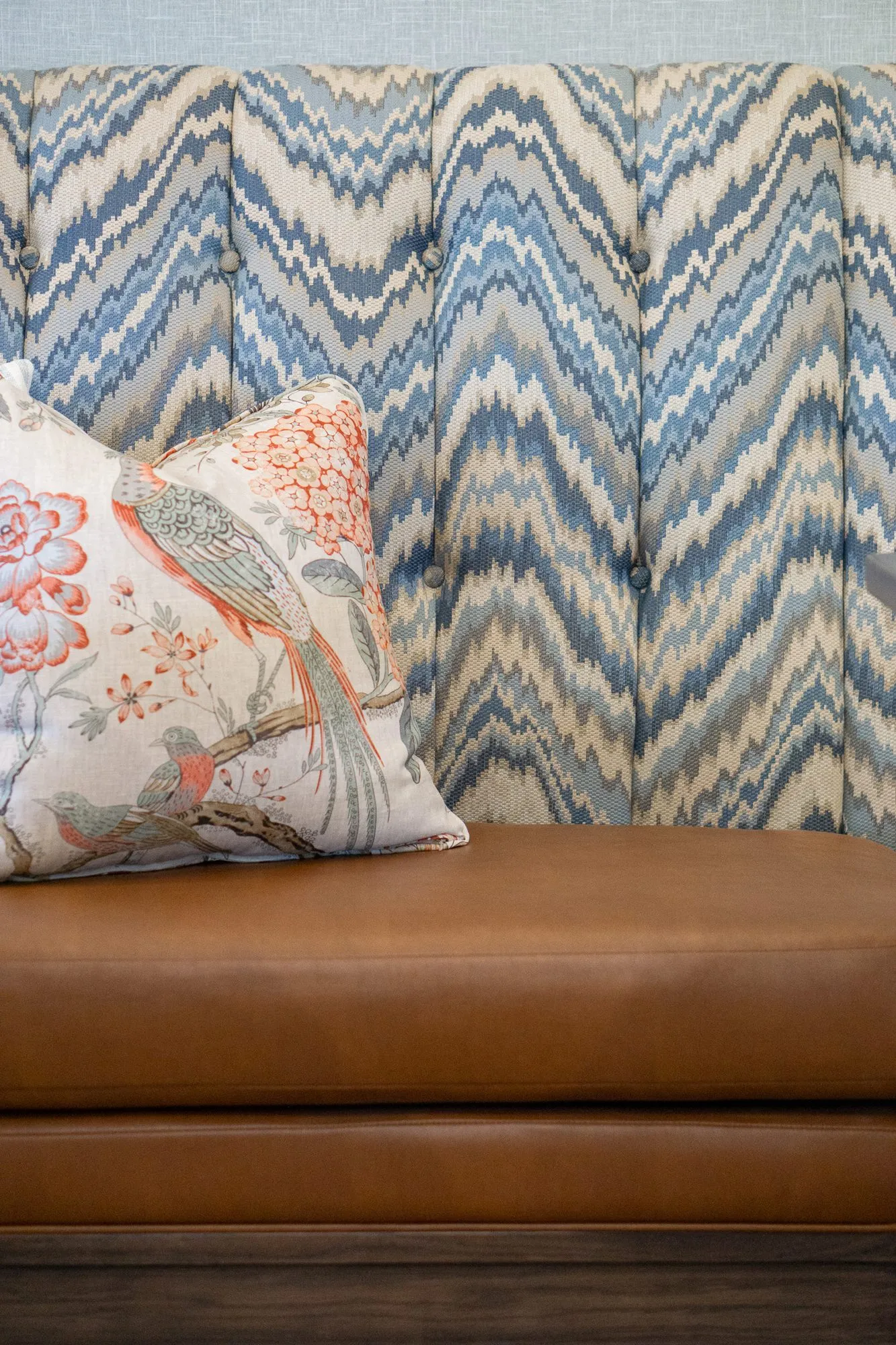 Senior living interior detail: bird print pillow on a tan leather banquette against a blue and cream chevron back
