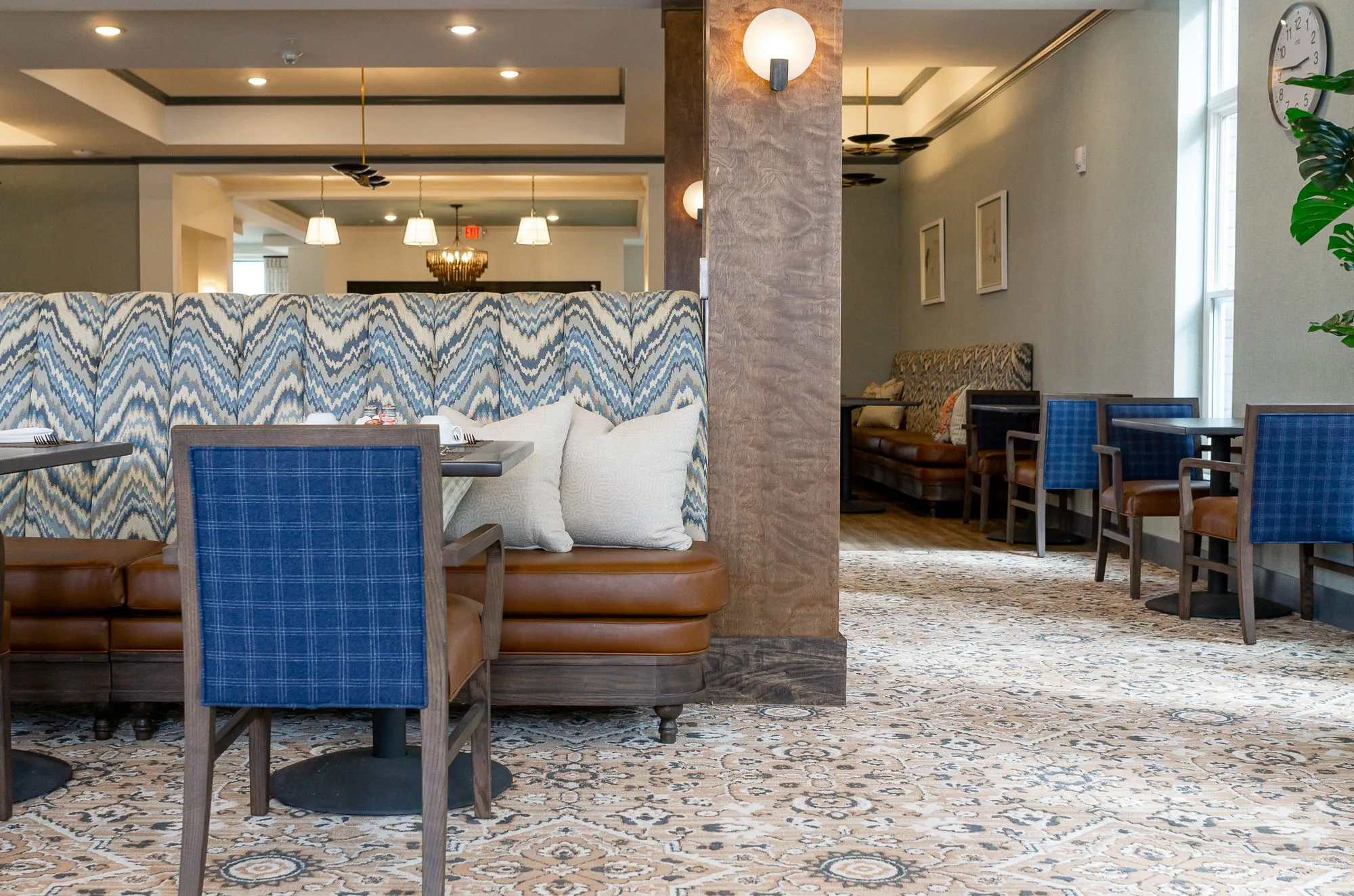 Senior living dining room, a blue plaid chair before the chevron banquette and a timber column with a globe sconce