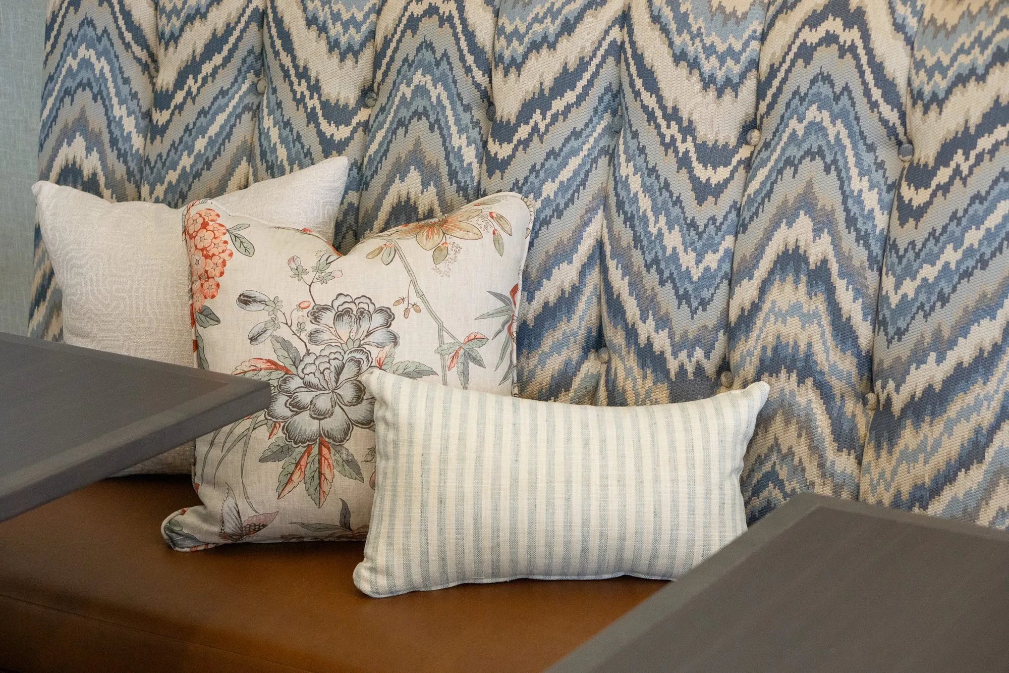 Senior living interior detail: floral, striped and cream pillows against the blue chevron banquette back