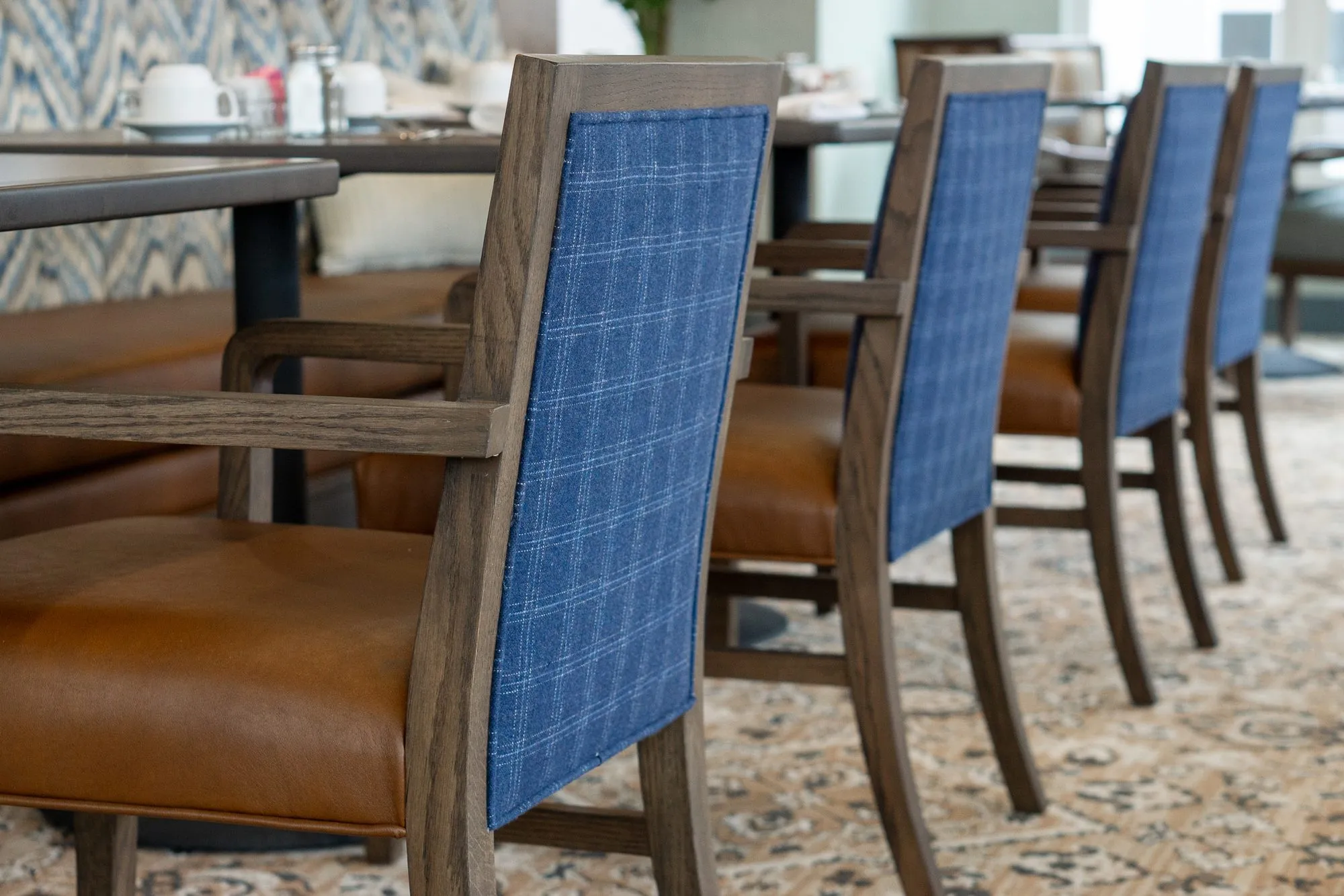 Senior living interior detail: row of blue plaid chair backs with tan leather seats along a table