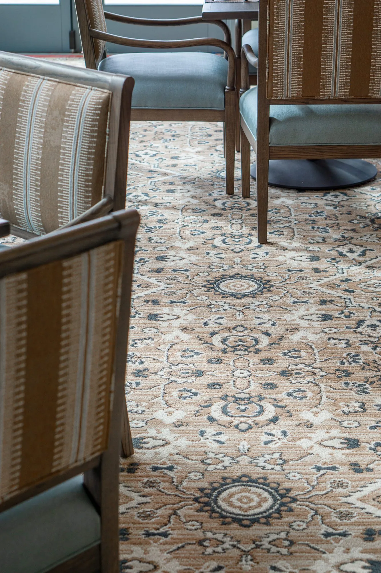Senior living interior detail: striped chair backs over the tan and navy medallion carpet
