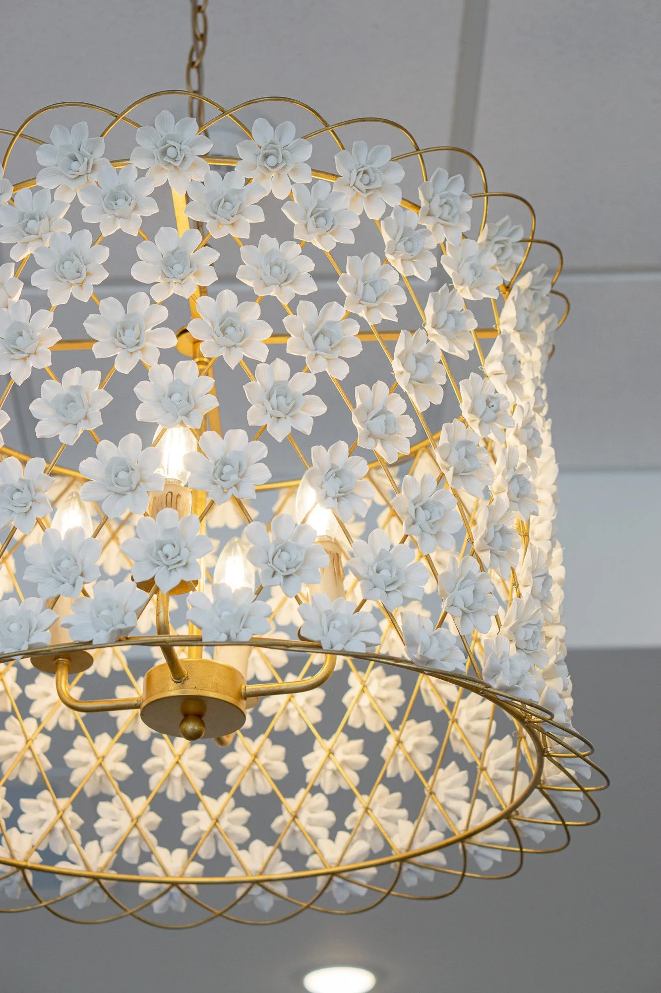 Senior living interior detail: gold chandelier covered in white porcelain flowers