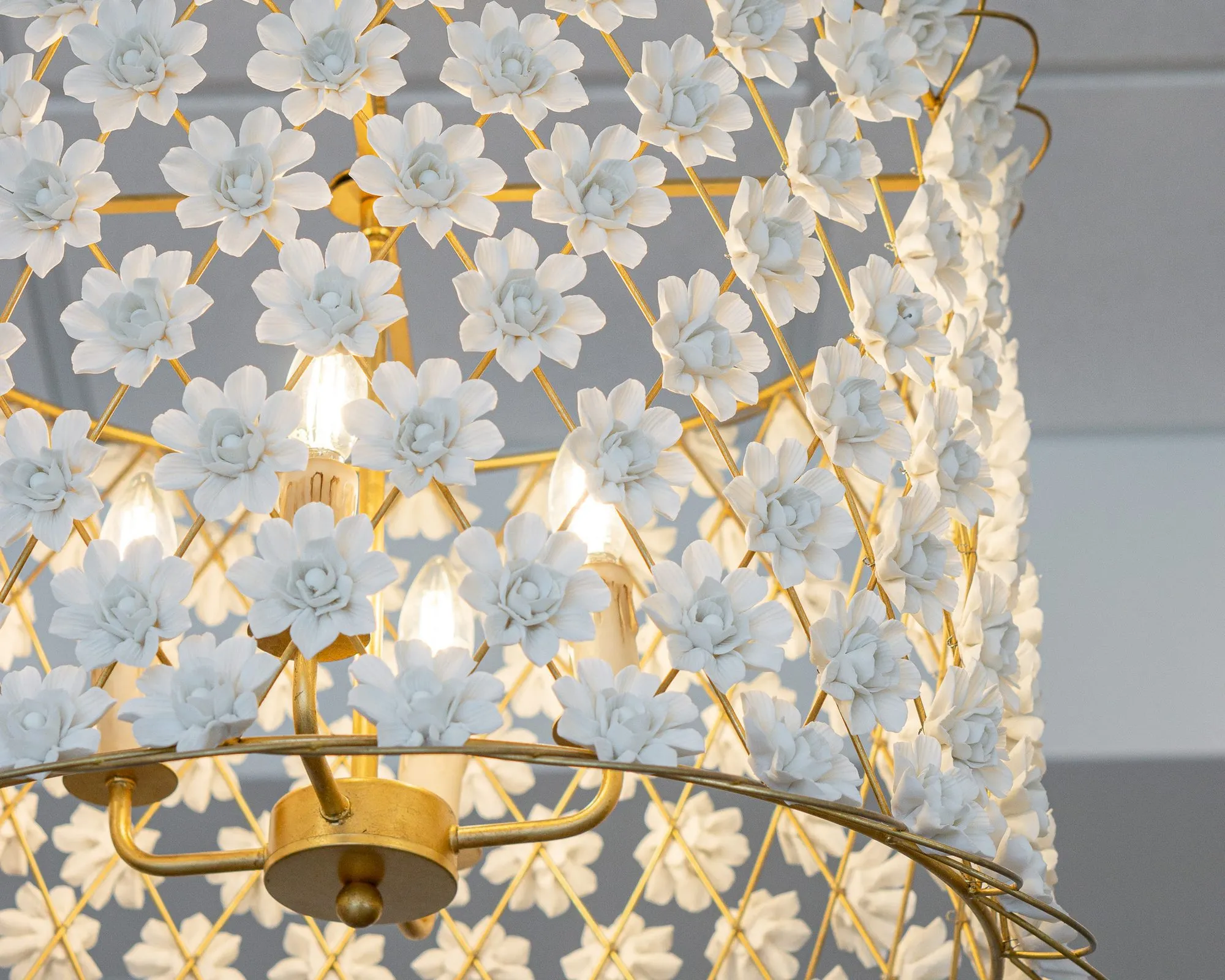 Senior living interior detail: white porcelain flowers on a gold wire chandelier frame