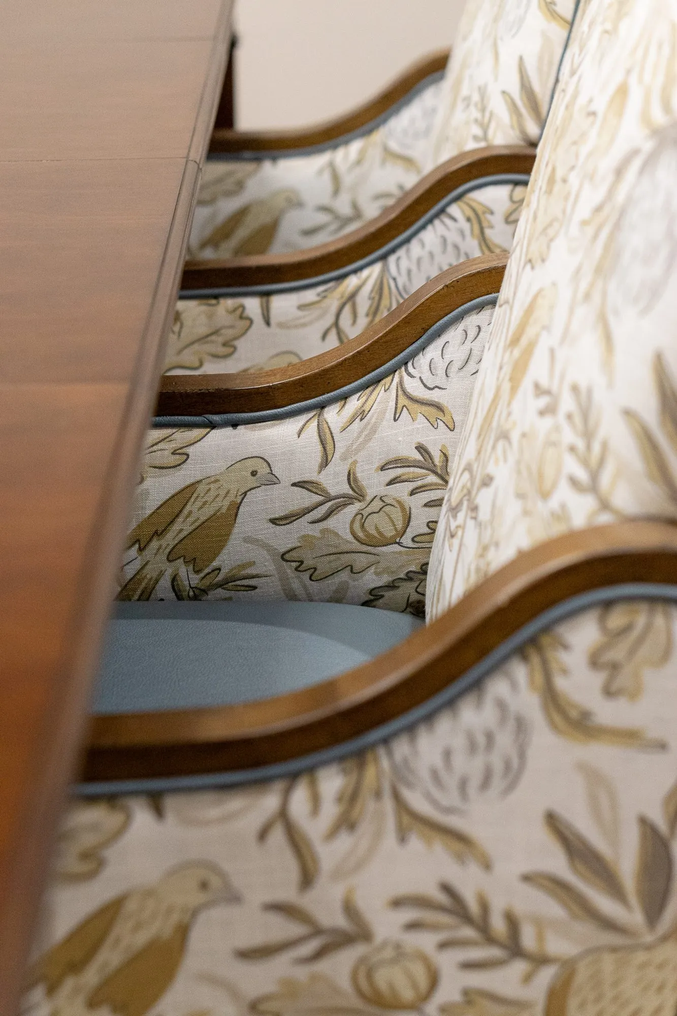 Senior living interior detail: row of bird print dining chairs with curved wood arms beside the table