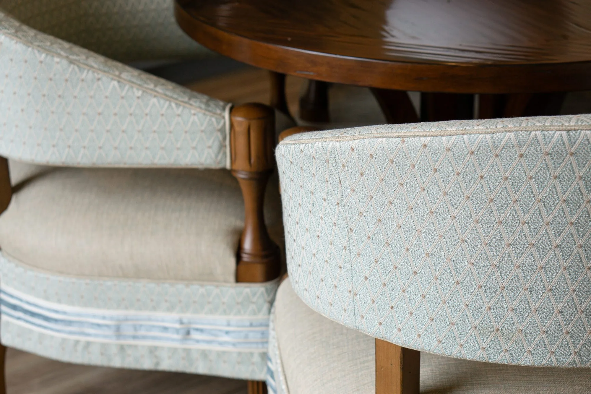 Senior living interior detail: diamond pattern barrel chair backs and a turned wood arm at the walnut table