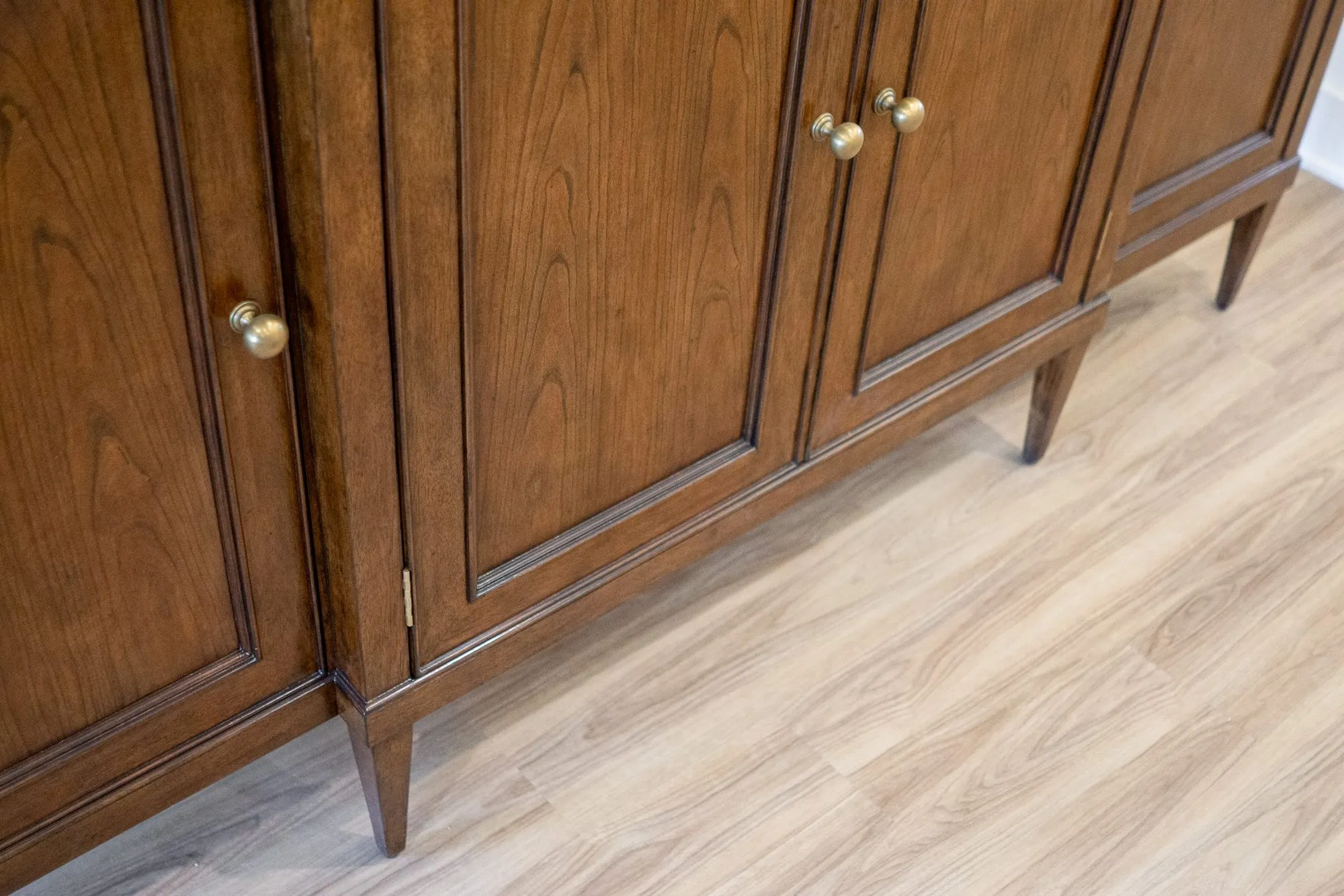 Senior living interior detail: walnut cabinet doors with brass knob pulls and tapered feet