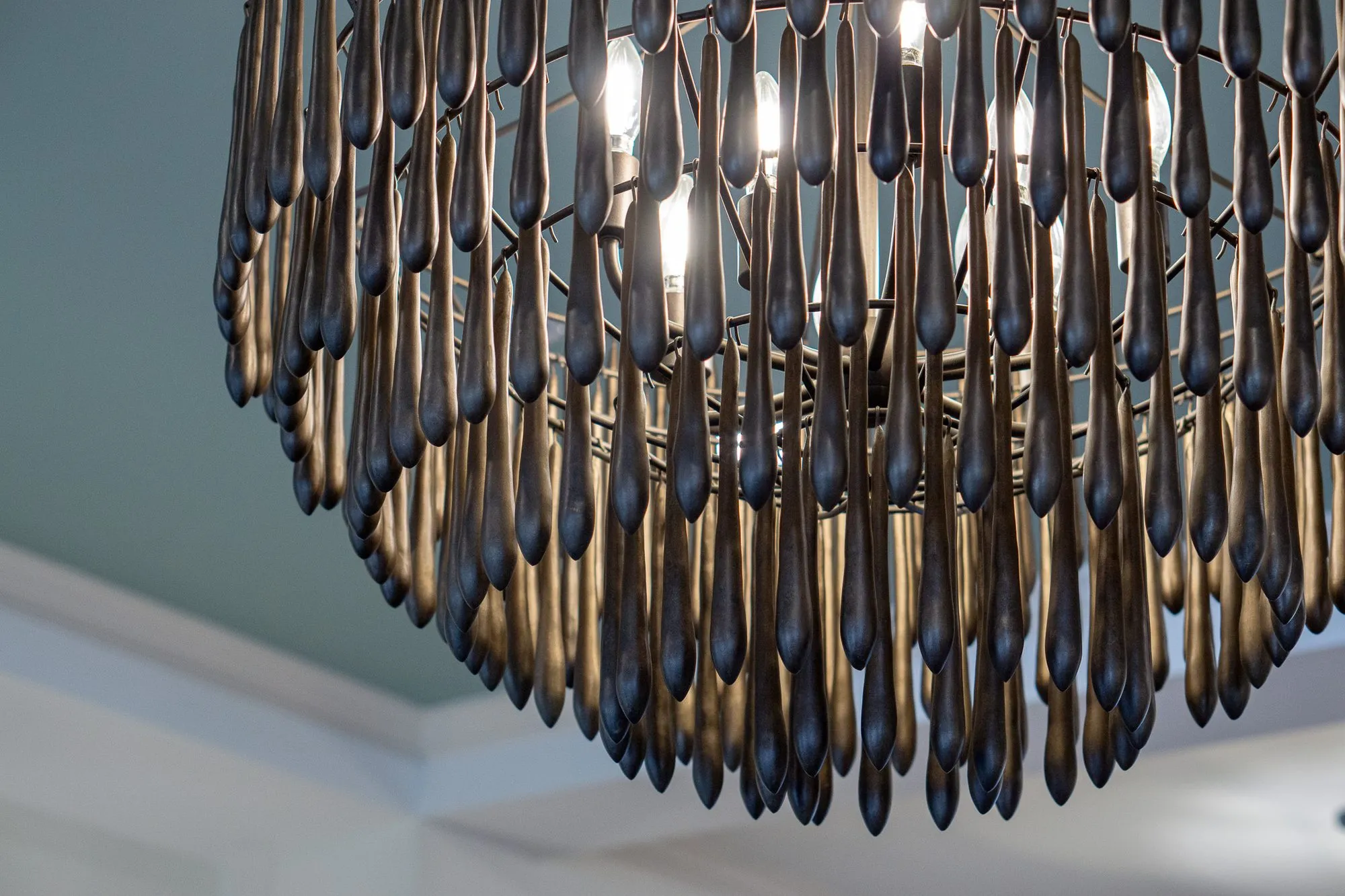 Senior living interior detail: wood bead chandelier's tiers of dark teardrop beads against an aqua ceiling