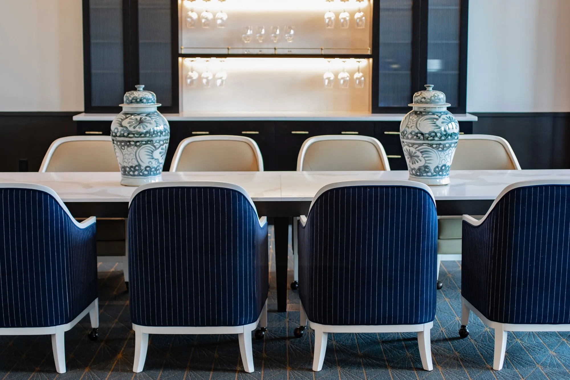 Senior living interior detail: navy pinstripe chairs along a marble table with blue and white ginger jars on top