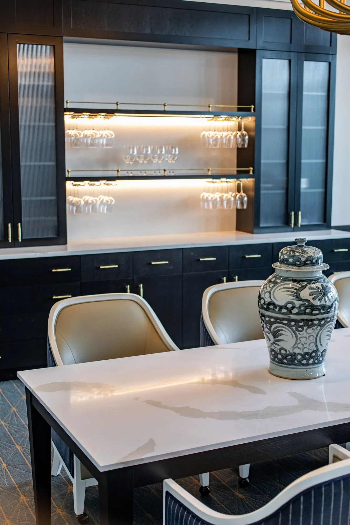 Senior living interior detail: blue and white ginger jar on a marble table before black cabinetry with lit glass shelves