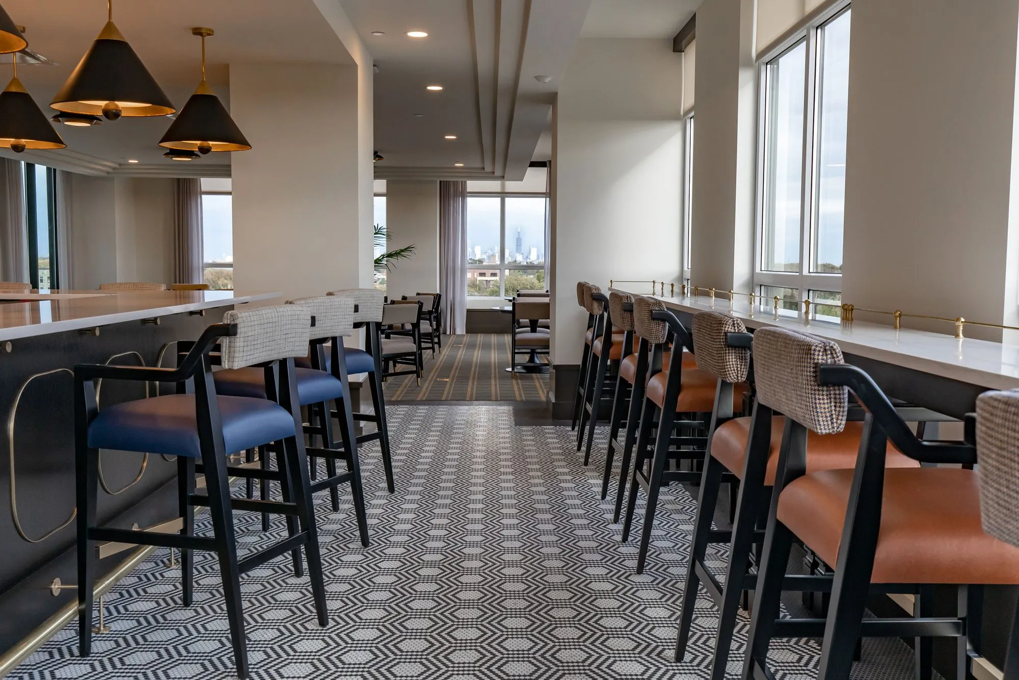 Senior living bistro with navy and cognac bar stools along two counters under black cone pendants on hexagon tile