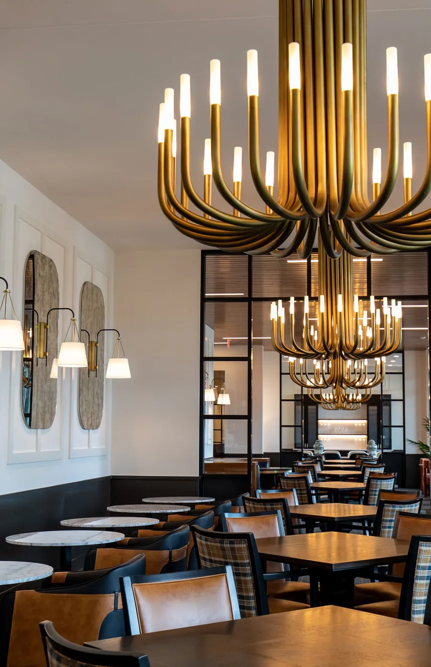 Senior living dining room with brass tube chandeliers and arched mirrors, interior design by Banko Design at American House Oak Park, Oak Park, Illinois