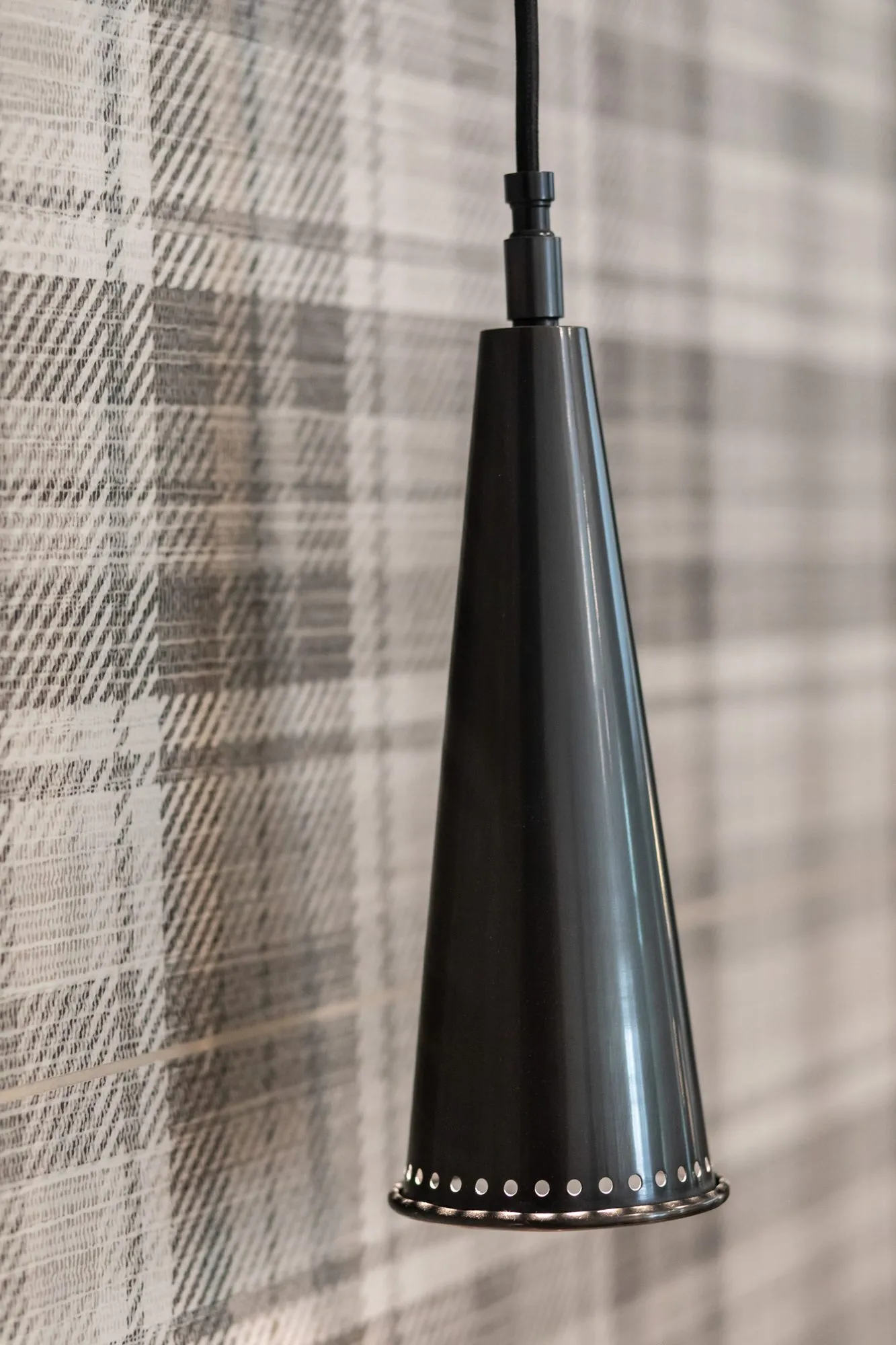 Active adult community interior detail: black cone pendant light against plaid wallpaper
