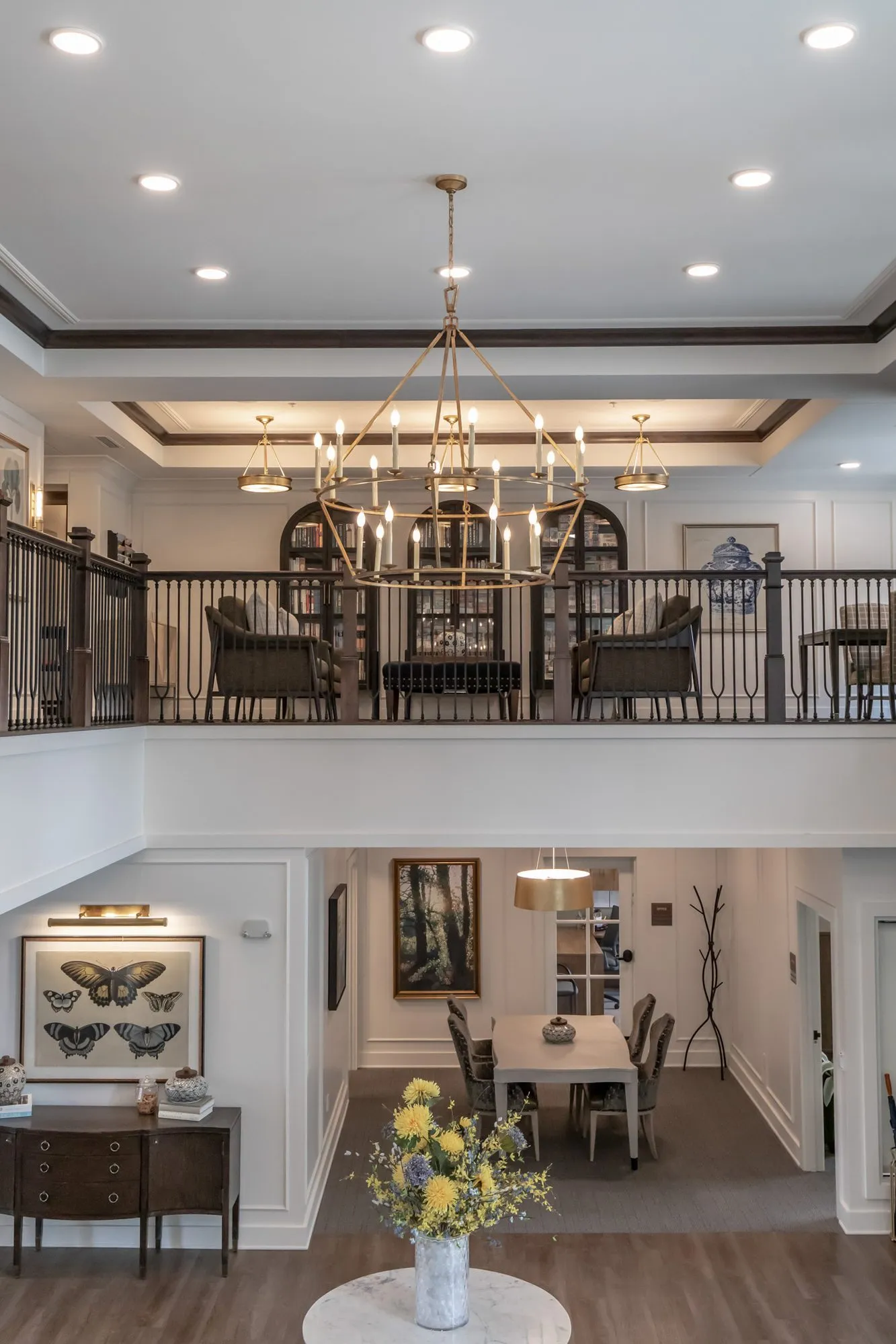Active adult community two-storey hall with a brass ring chandelier over the mezzanine lounge and dining room below
