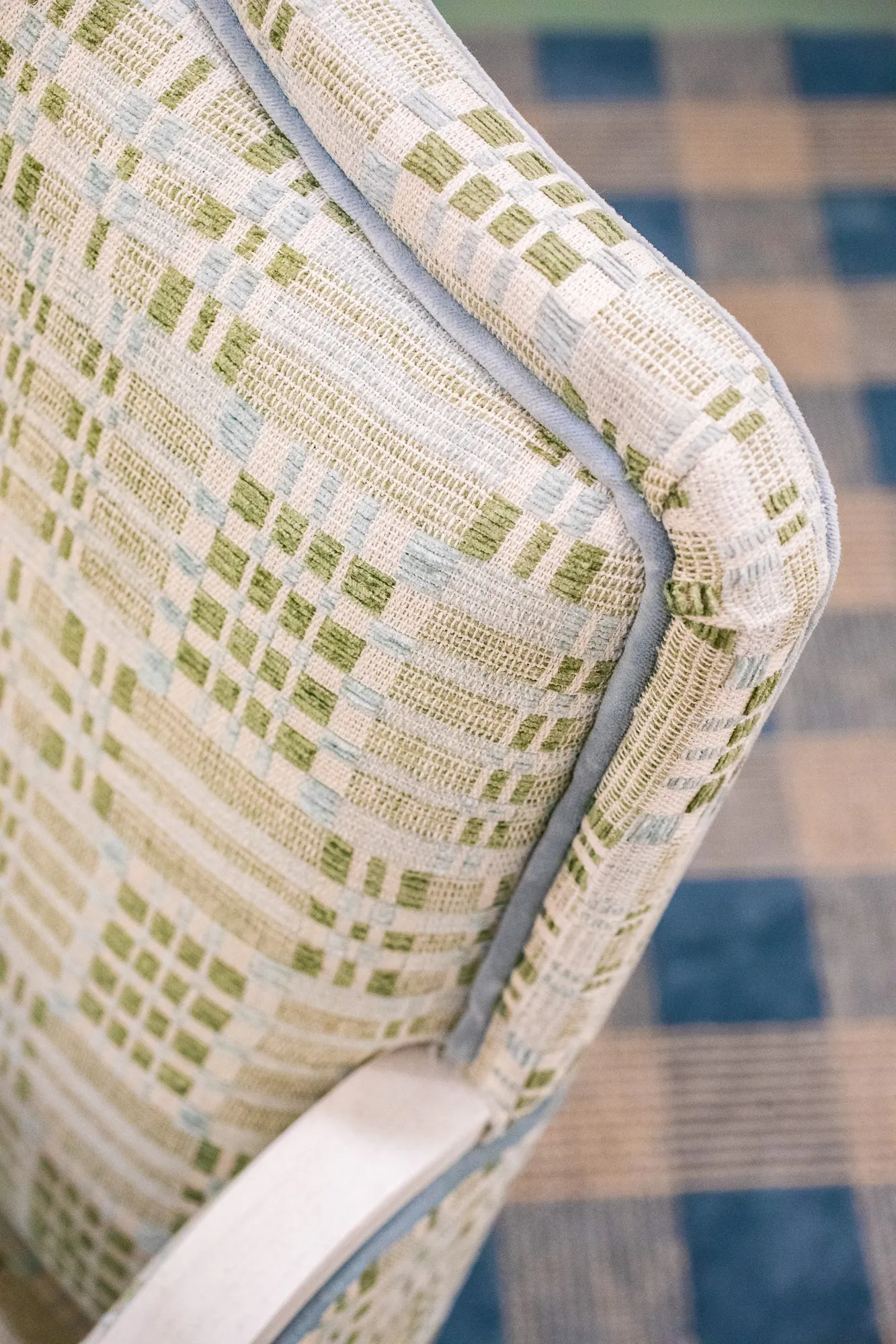 Senior living interior detail: green and cream woven upholstery with blue piping on a chair