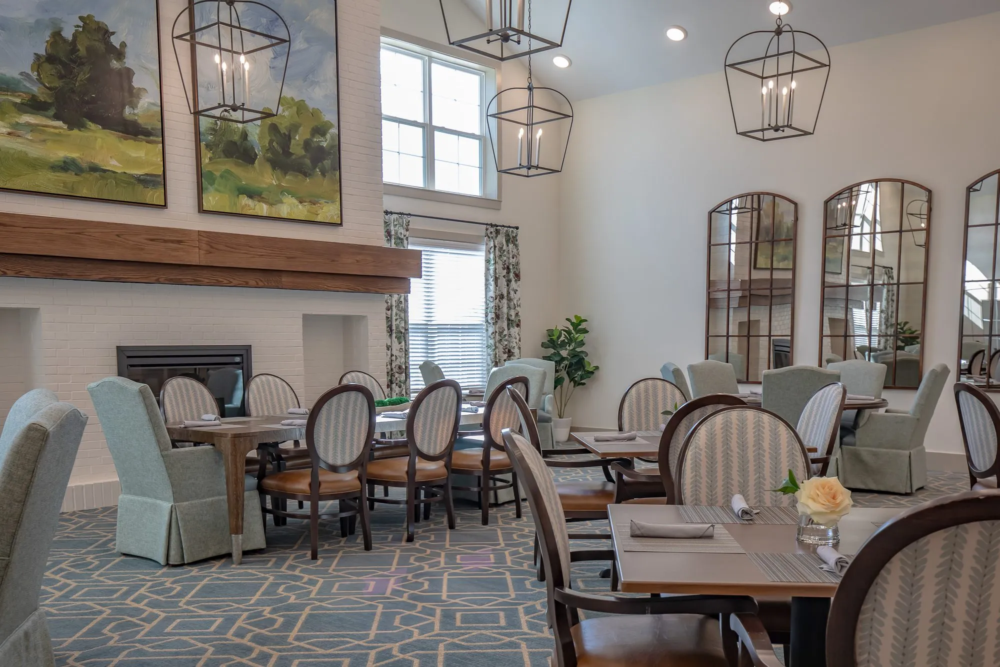 Senior living dining room detail: table set for dining with oval back and sage skirted chairs, fireplace and mirrors beyond