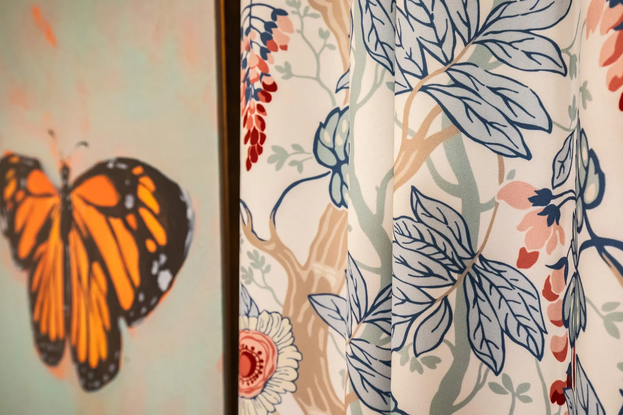Senior living interior detail: butterfly painting beside drapery printed with blue leaves and coral flowers