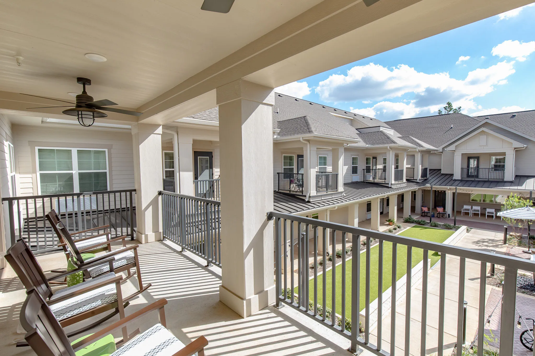 Senior living covered porch with wood rocking chairs on the upper gallery looking over the courtyard lawn