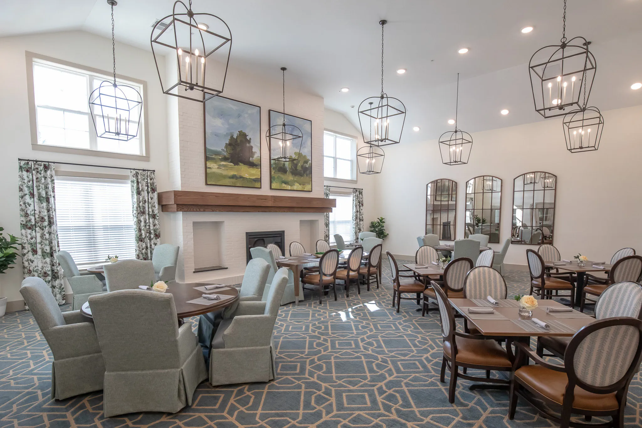 Senior living dining room with lantern pendants under a vaulted ceiling, arched mirrors and sage skirted chairs