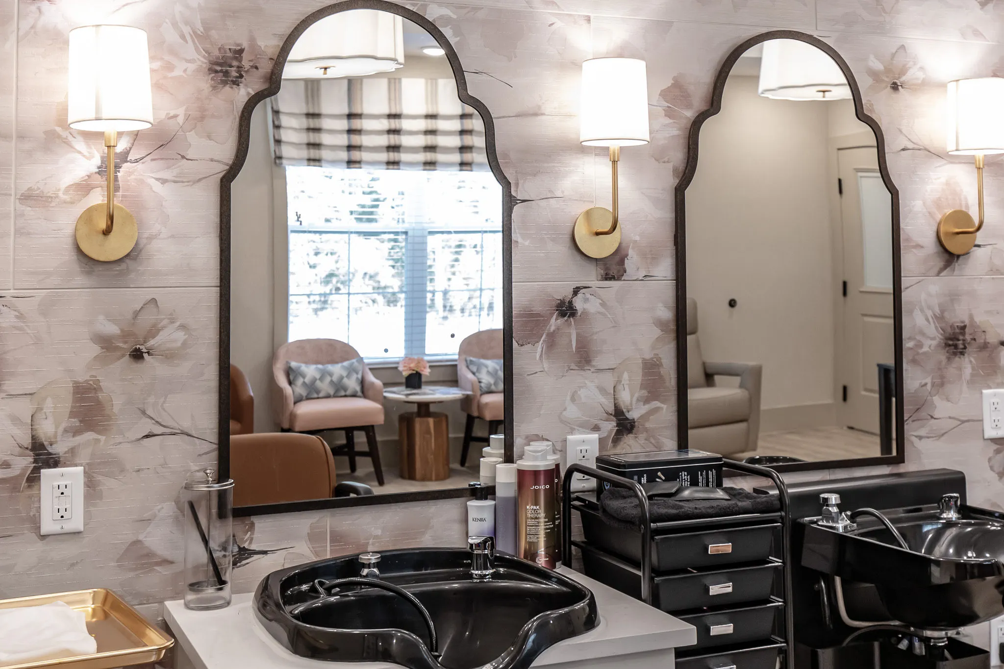 Senior living salon with arched mirrors and brass sconces above the shampoo bowls on a large watercolour floral wallcovering