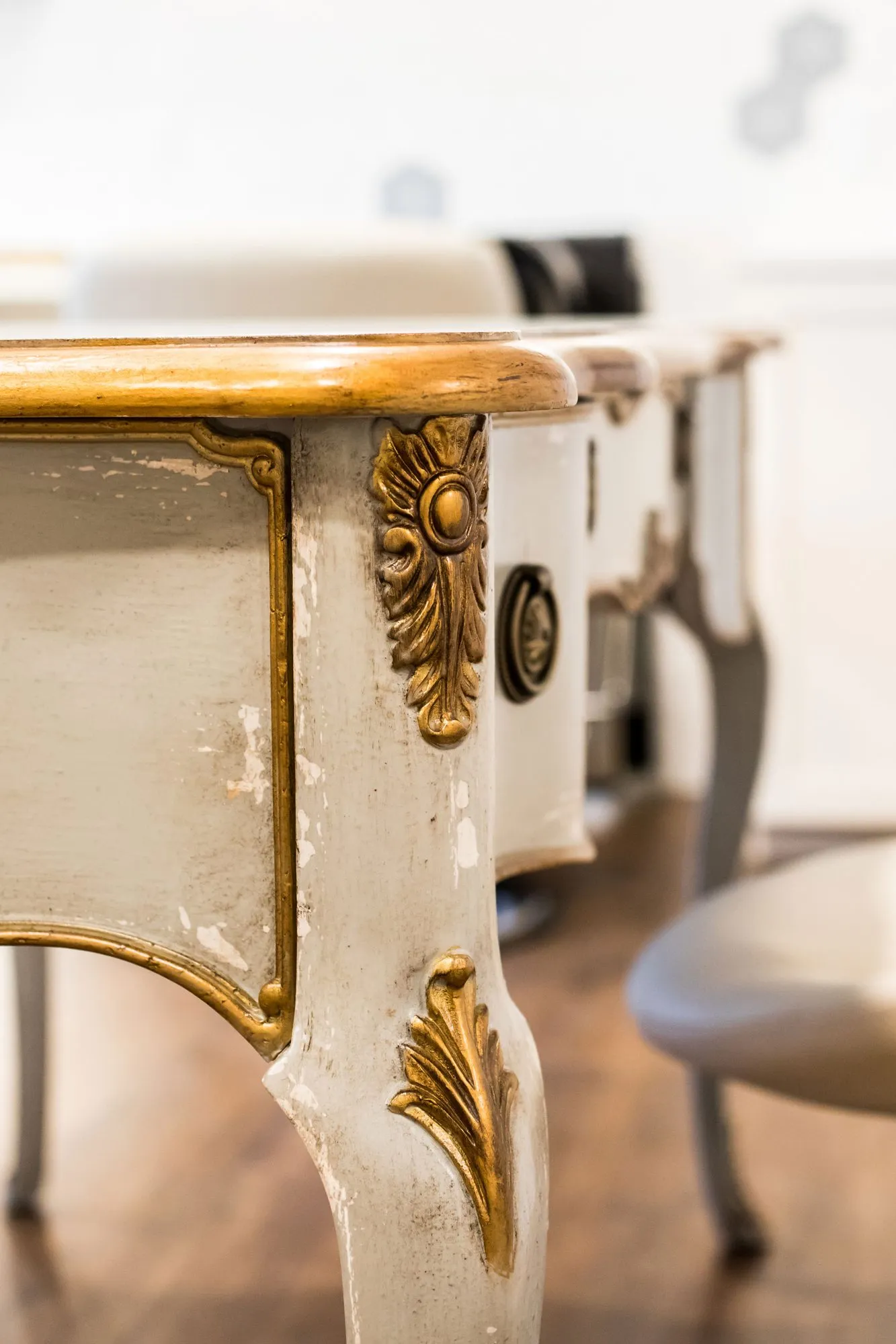 Senior living interior detail: cream painted table leg with gilt carved scrollwork, interior design by Banko Design at The Blake At Waco, Waco, Texas