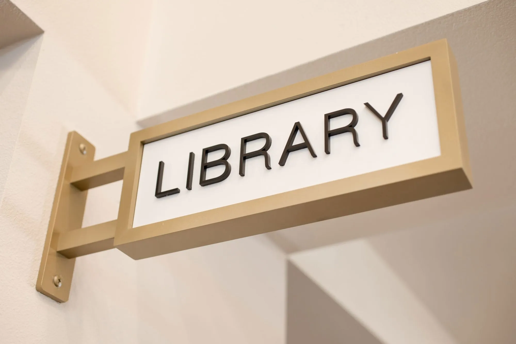 Senior living interior detail: brass projecting room sign reading Library