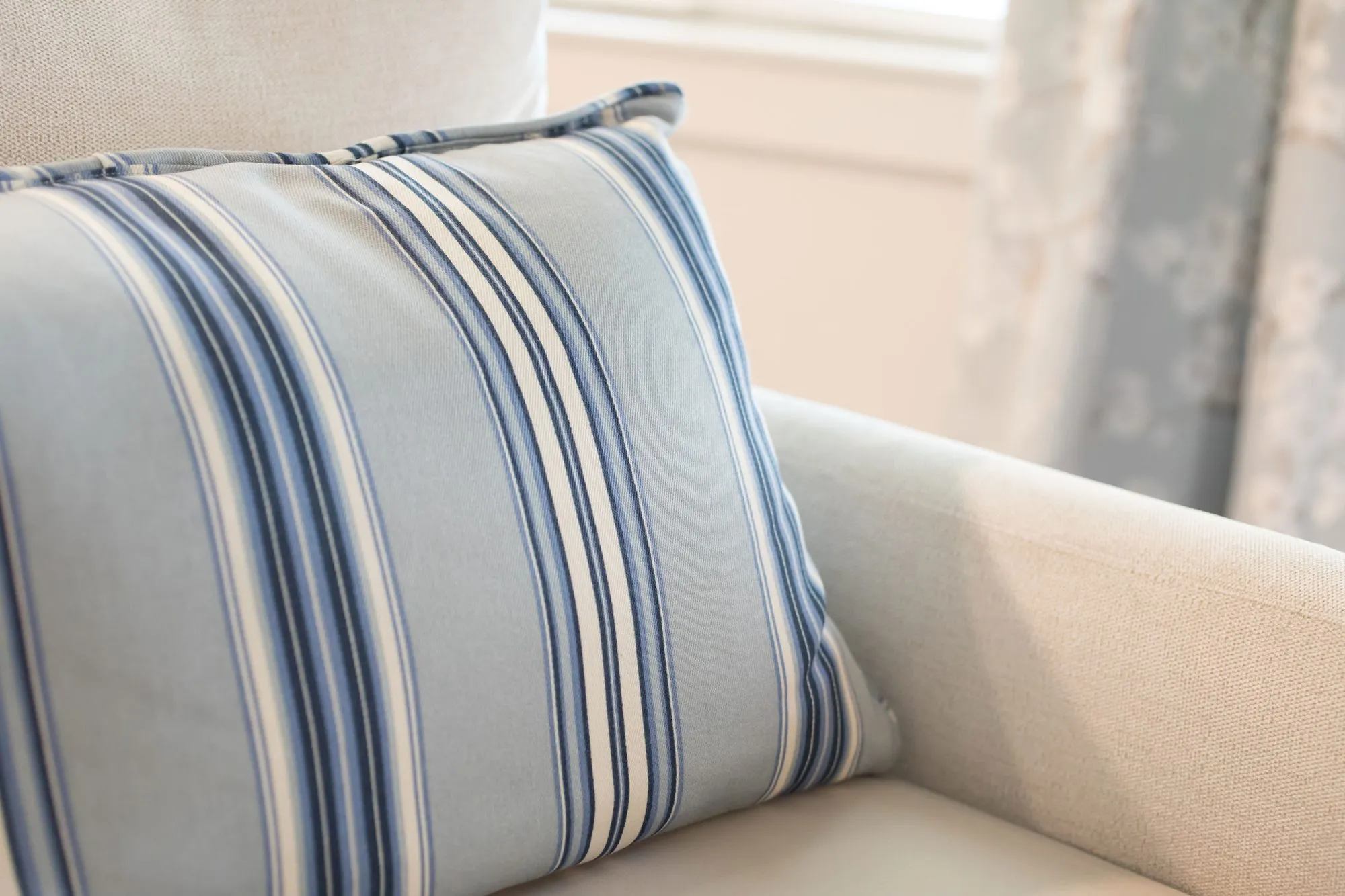 Senior living interior detail: blue and white striped pillow on a pale linen chair