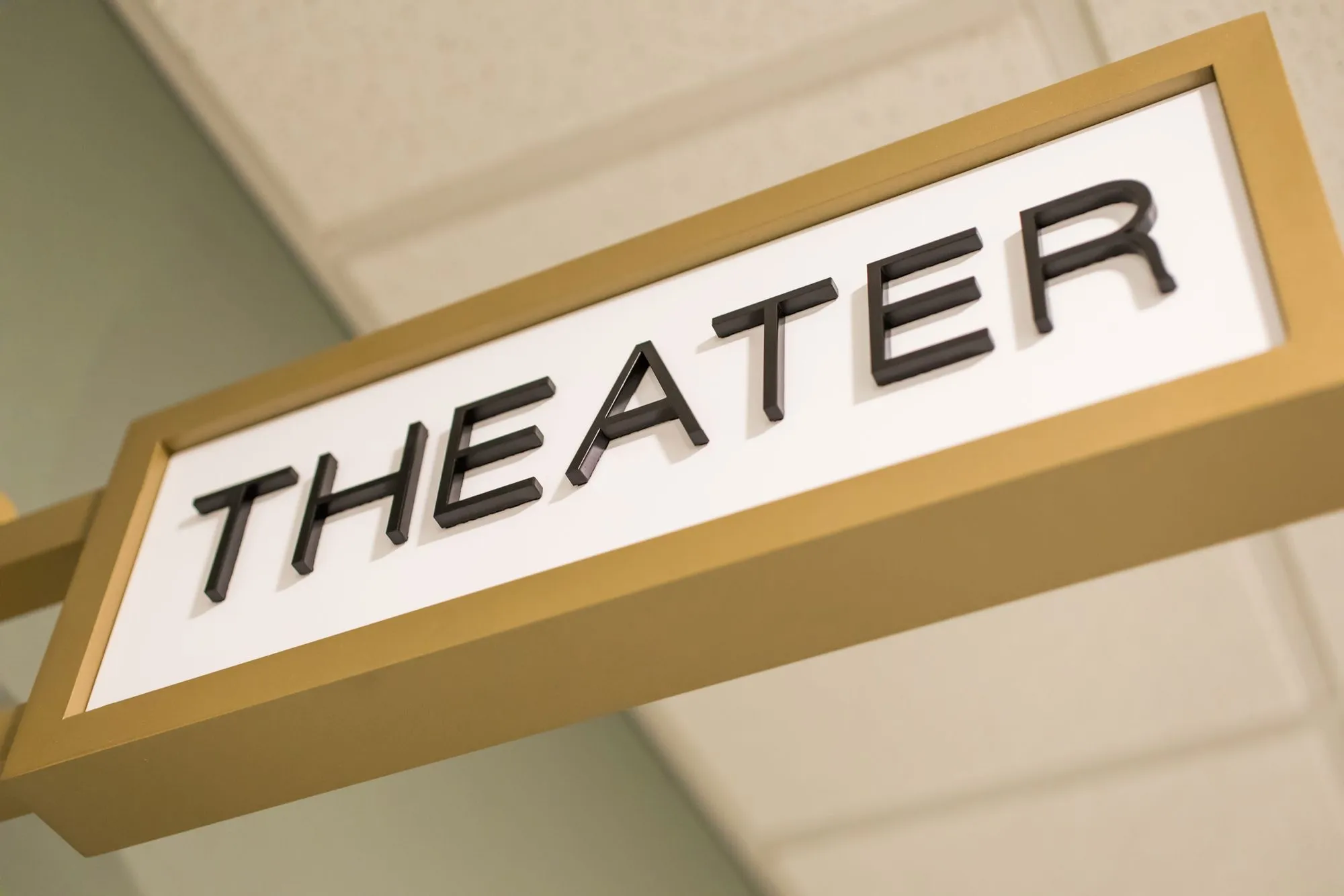 Senior living interior detail: brass projecting room sign reading Theater