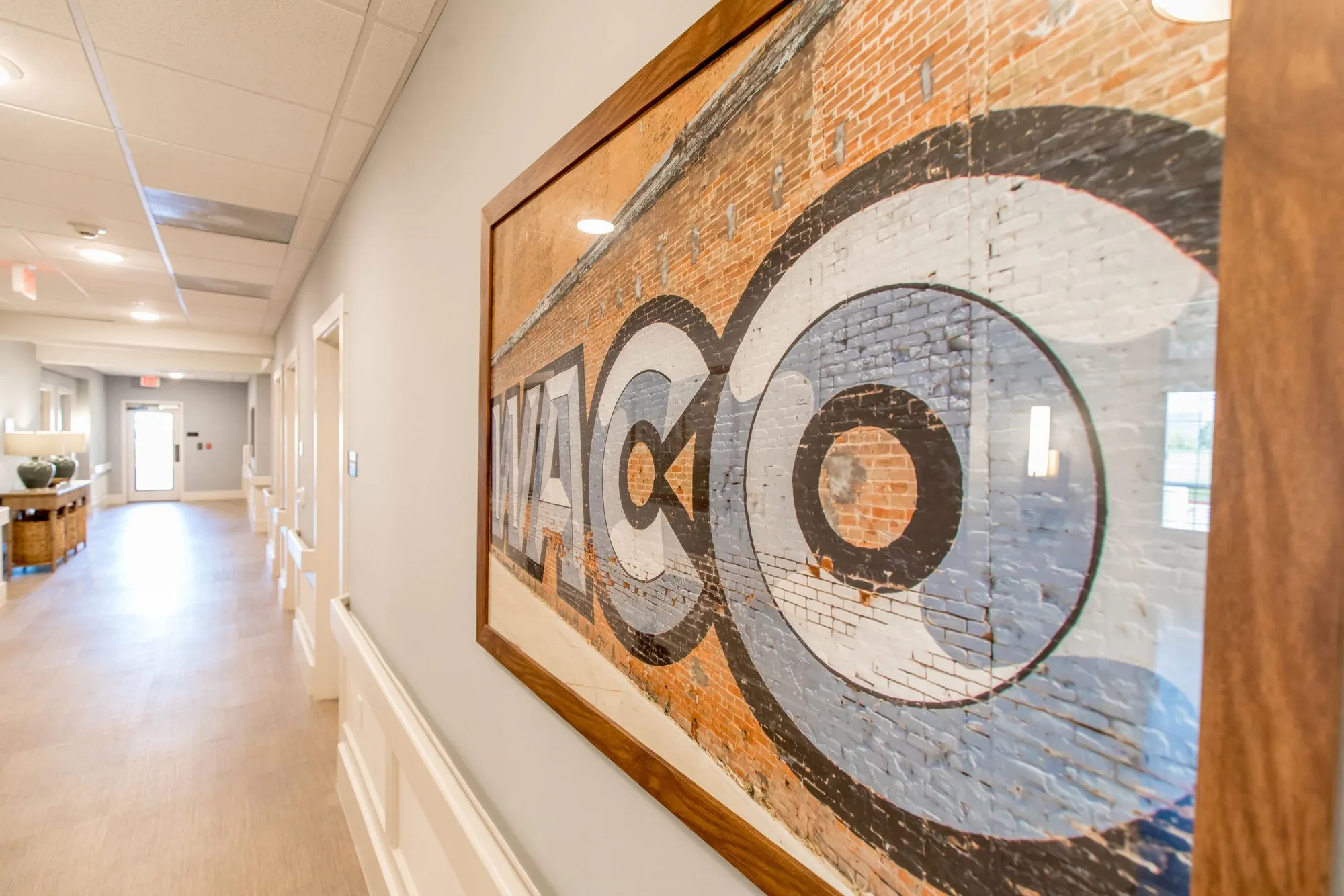 Senior living corridor hung with a long framed photograph of a painted brick wall sign