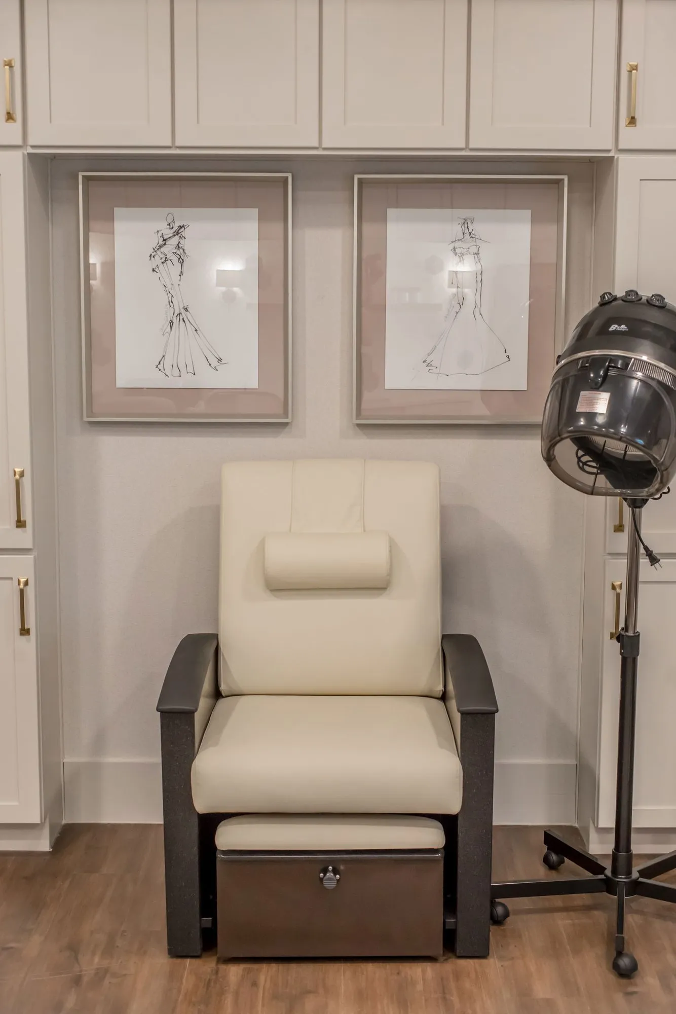 Senior living salon with a cream leather pedicure chair beside a hood dryer, two framed fashion sketches above