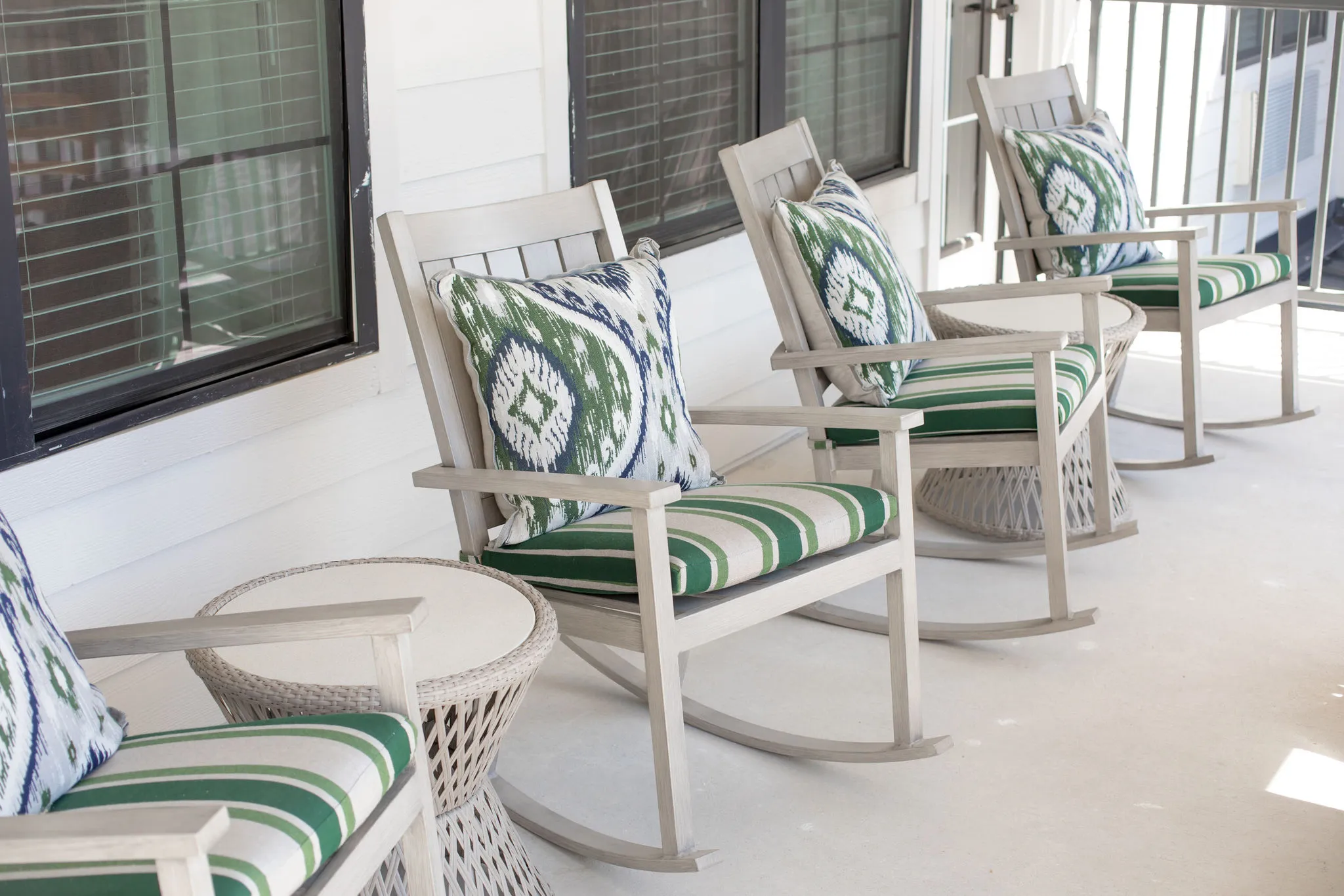 Senior living covered porch with green striped rocking chairs and ikat pillows along the shiplap wall