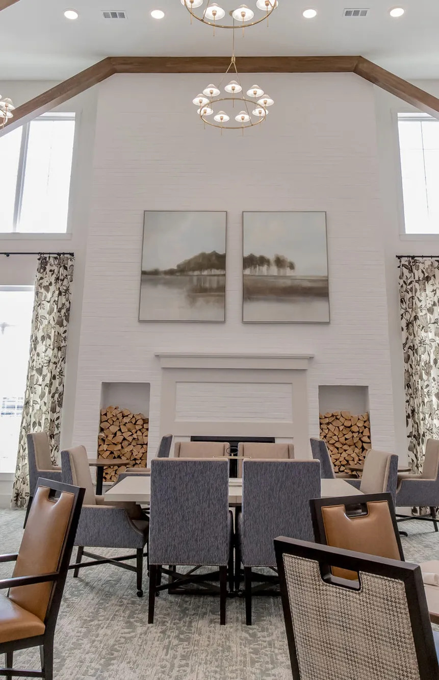 Senior living dining room with a shiplap ceiling, white brick fireplace and ring chandeliers, interior design by Banko Design at The Blake At Waco, Waco, Texas
