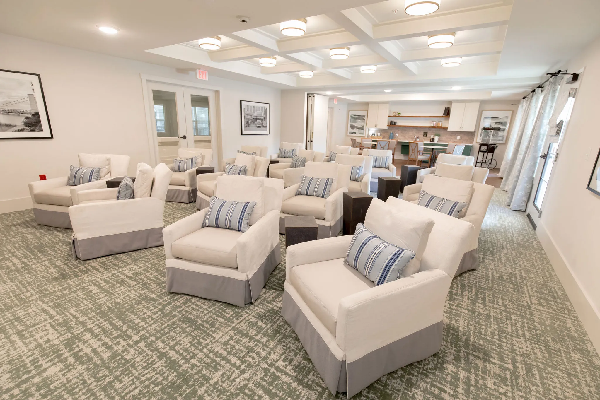 Senior living theater with cream skirted armchairs and striped pillows on a moss green carpet
