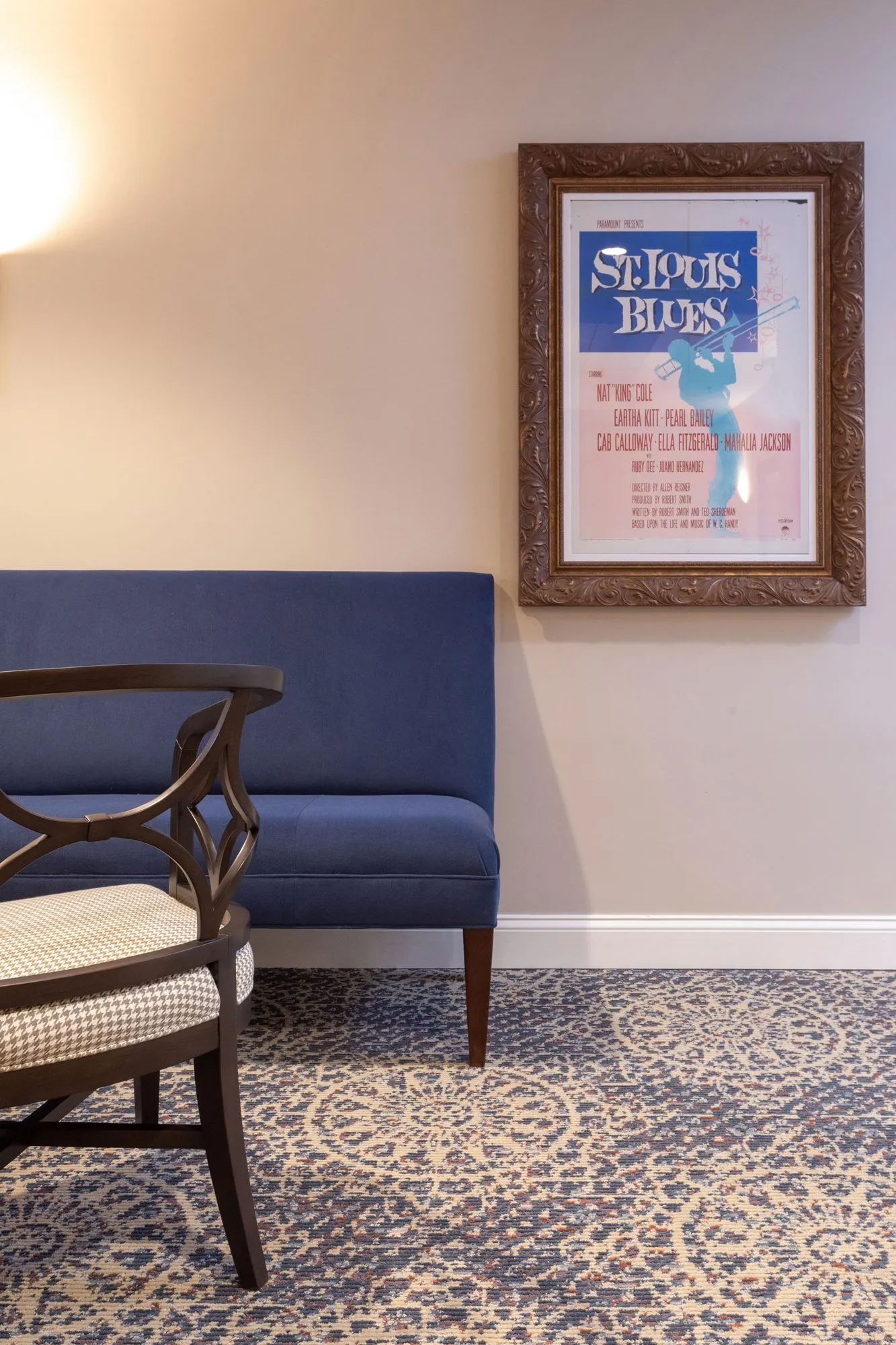Senior living interior detail: navy bench and checked-seat armchair below a film poster, interior design by Banko Design at Cadence At Olney, Olney, Maryland