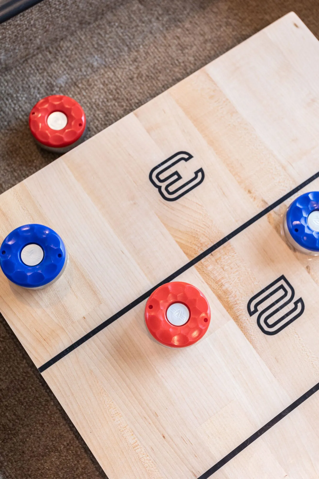 Senior living game room shuffleboard, red and blue pucks on a maple board marked with scoring numbers