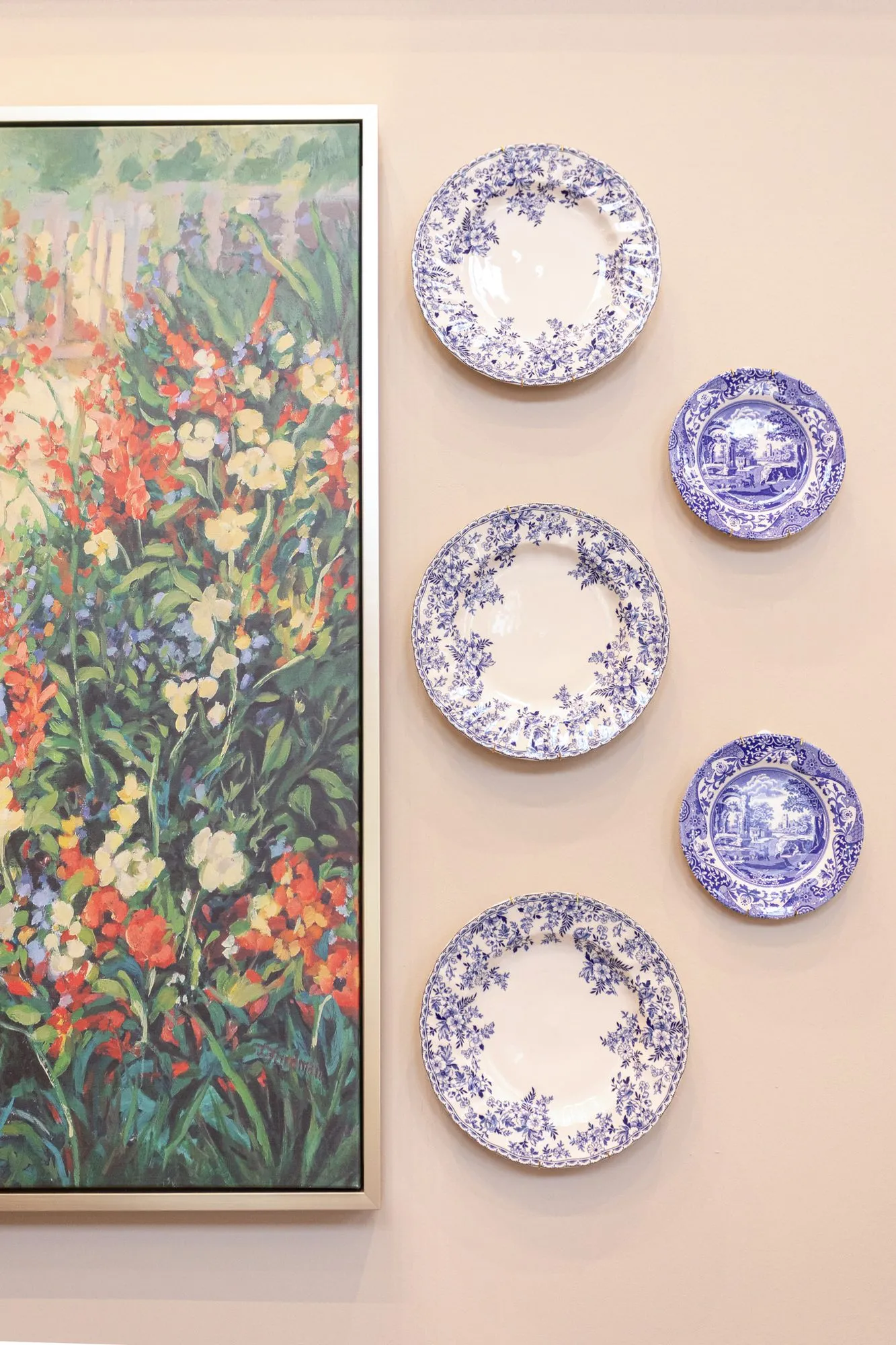 Senior living interior detail: floral garden painting beside a column of blue and white transferware plates