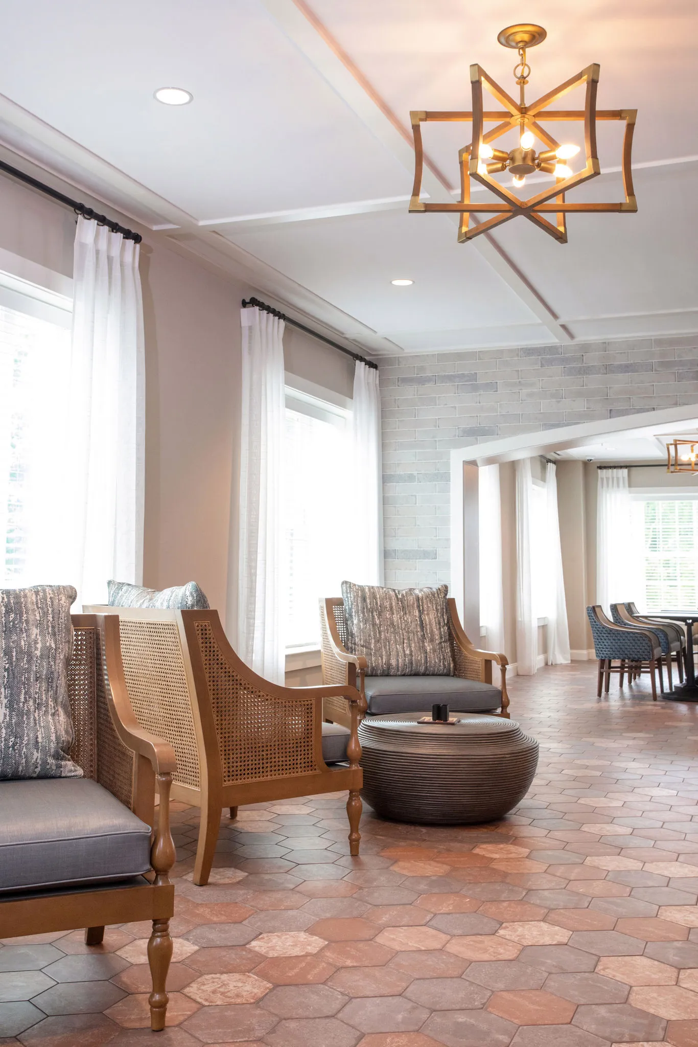 Senior living sunroom with cane lounge chairs on hexagonal terracotta tile below a brass lantern