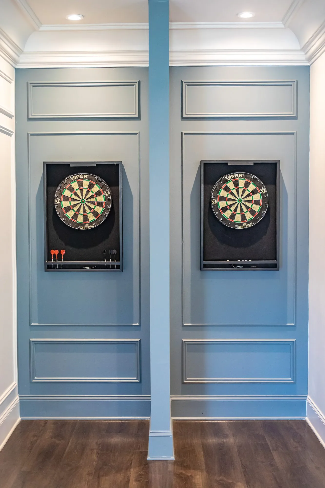 Multifamily amenity clubroom with two dartboards in black cabinets on pale blue panelled doors