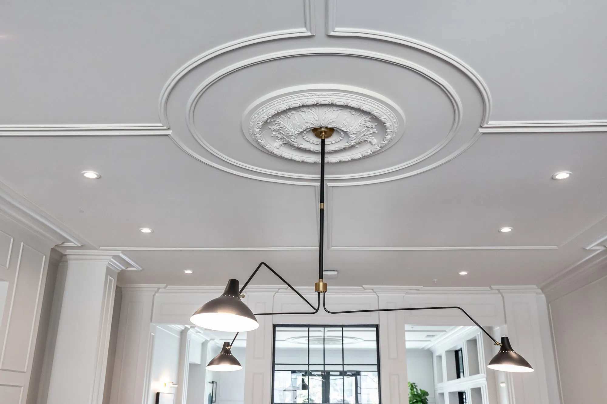 Multifamily amenity interior detail: black multi-arm ceiling light hanging from a plaster medallion and circular moulding
