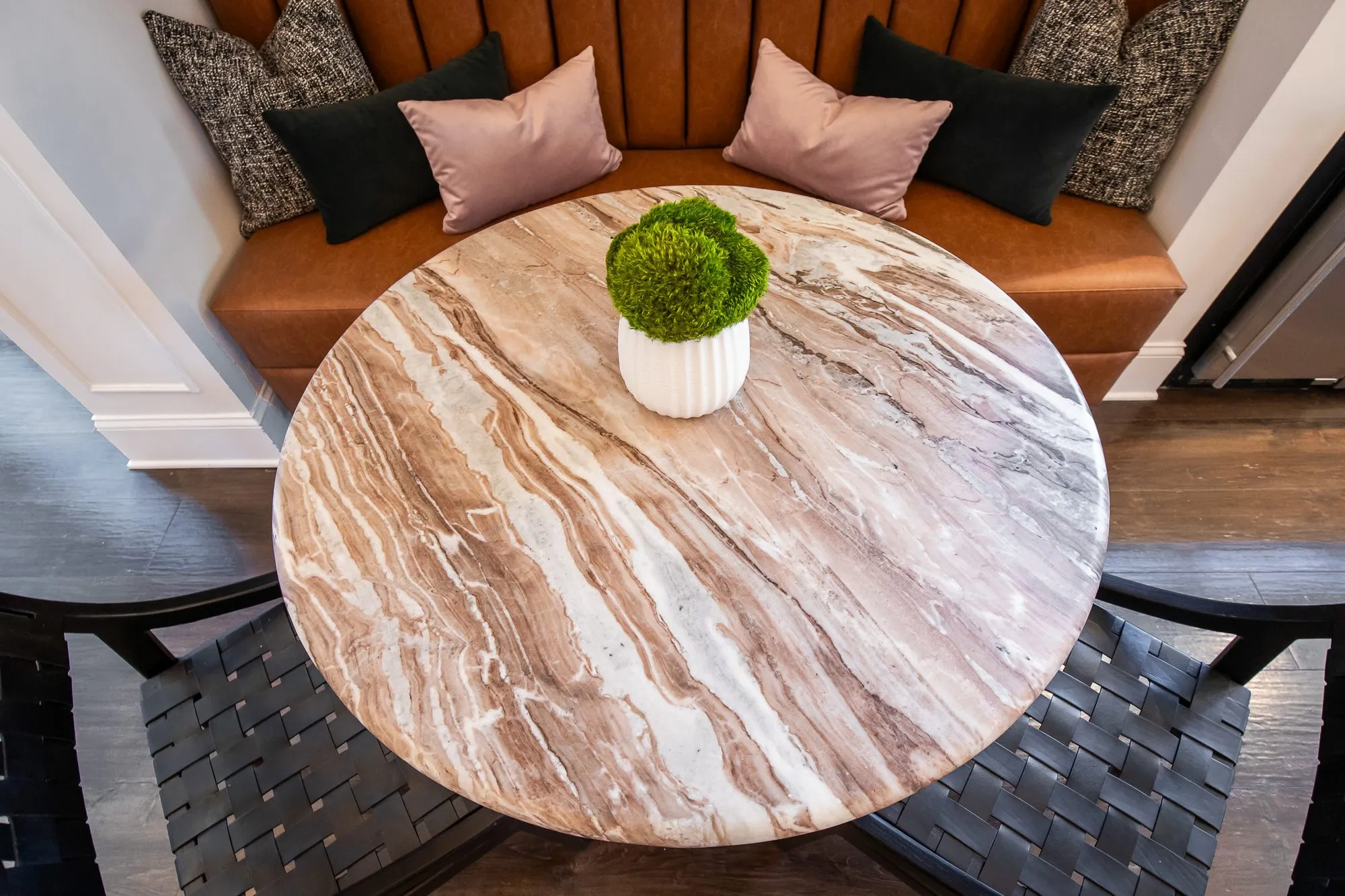 Multifamily amenity interior detail: marble table with a moss topiary before a cognac banquette with black and pink pillows