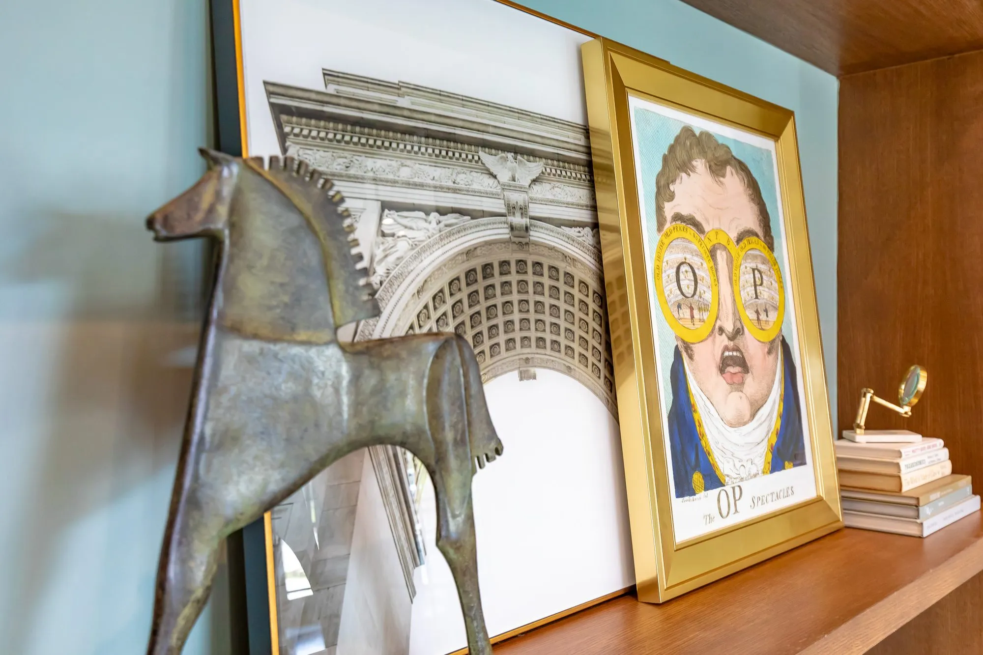 Multifamily interior detail: shelf with a bronze horse before a classical arch print and a gilt-framed pop art portrait