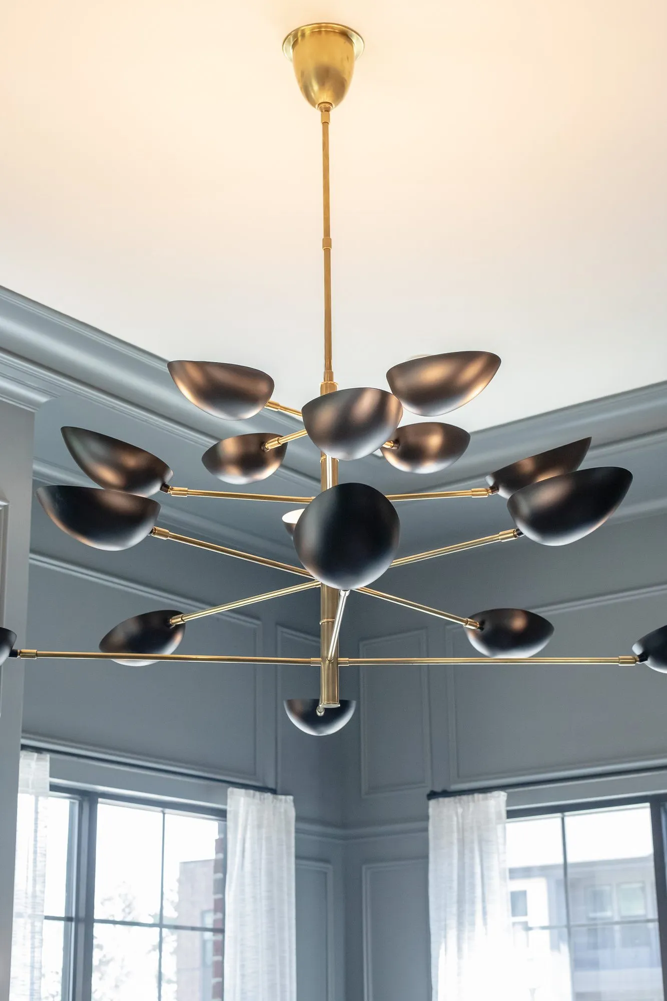 Multifamily amenity interior detail: brass chandelier of black dome shades against grey panelled walls
