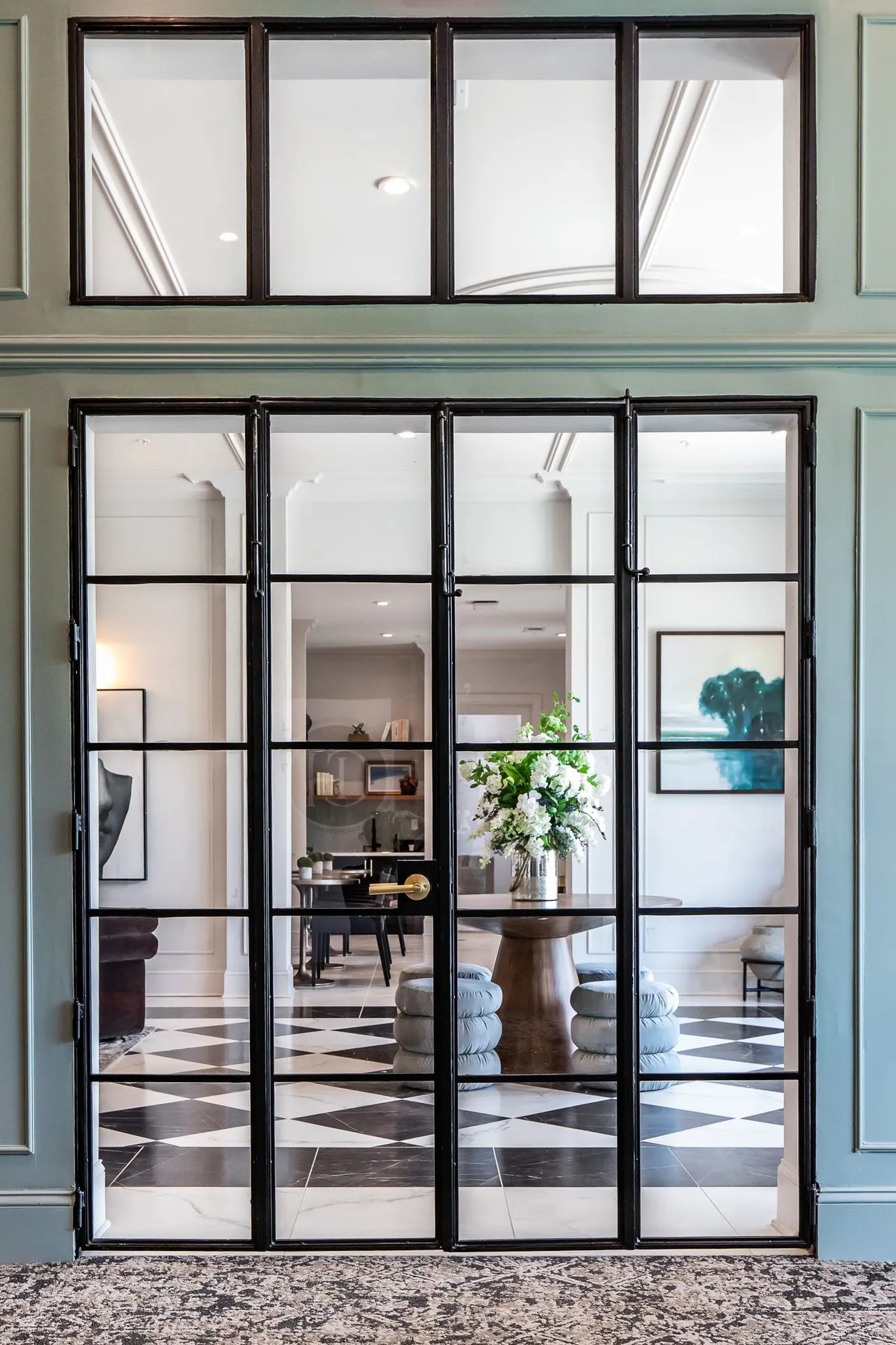 Multifamily amenity leasing office with black steel French doors in sage panelling, the checkerboard lobby through the glass