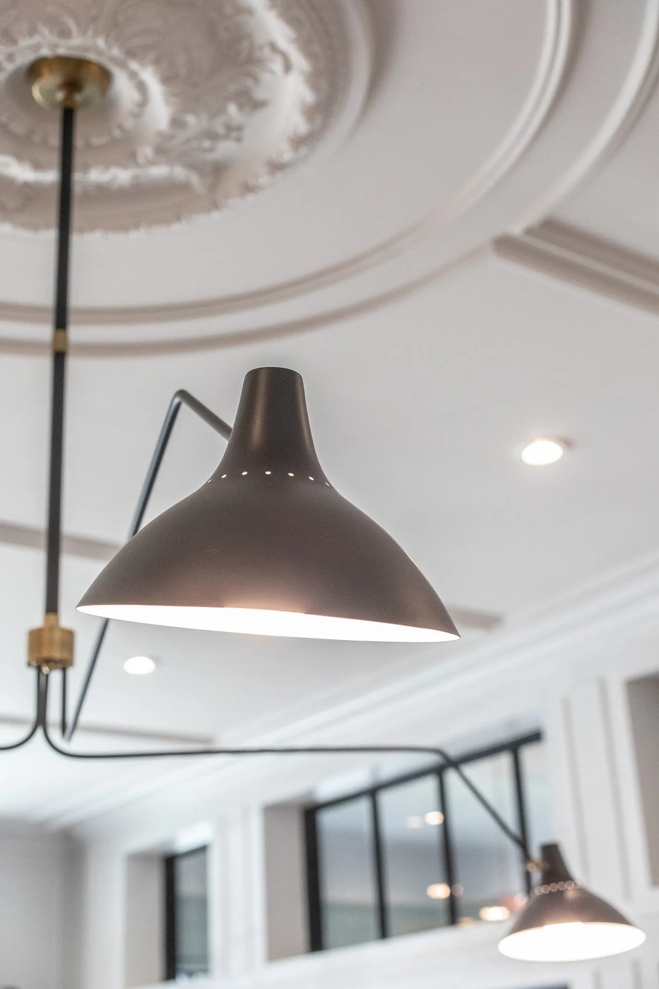 Multifamily amenity interior detail: black multi-arm ceiling light hanging from a plaster medallion