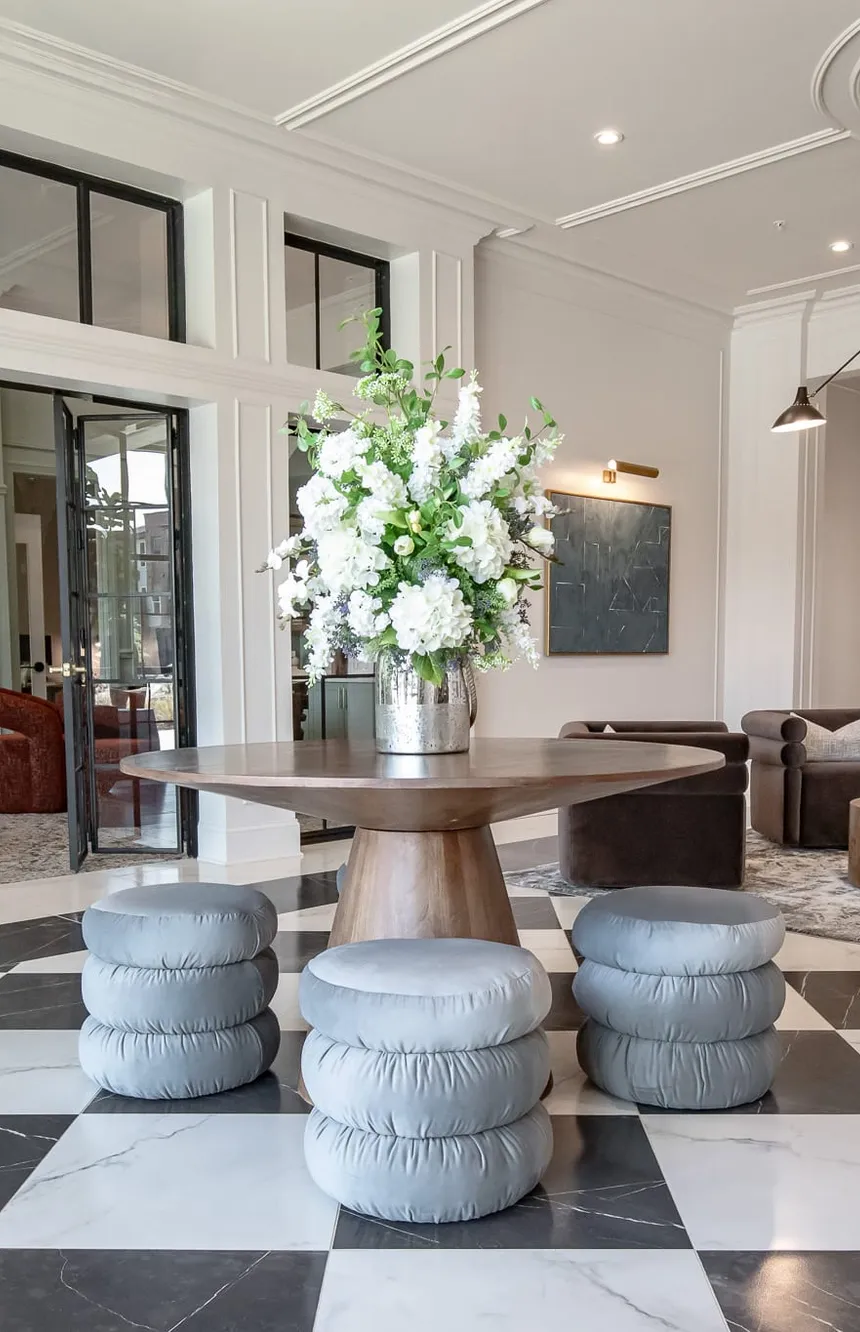 Multifamily amenity lobby on checkerboard marble with a round table of white flowers, interior design by Banko Design at Chastain Hill, Douglasville, Georgia