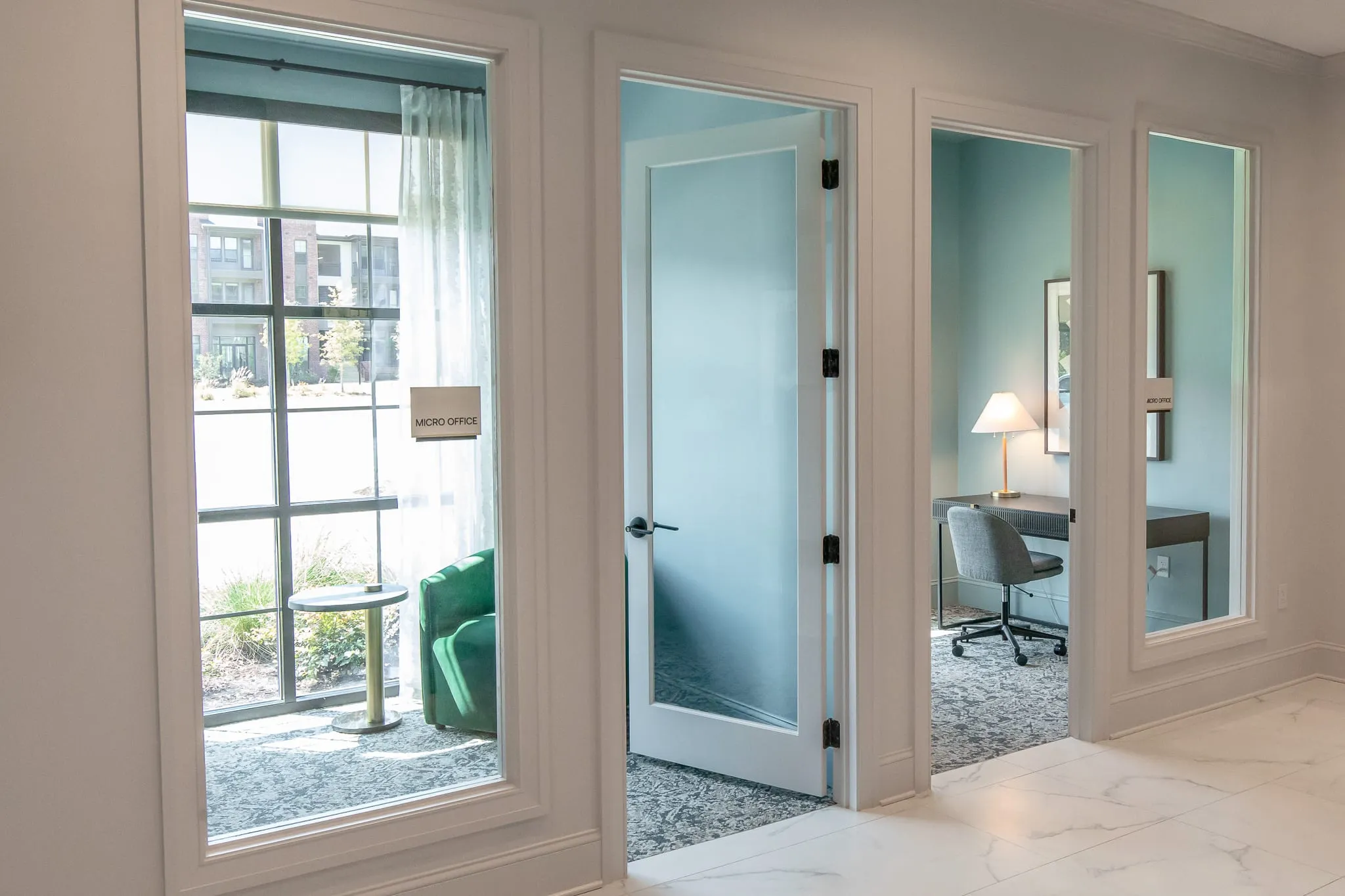 Multifamily amenity micro offices with pale blue frosted glass doors opening onto private desks