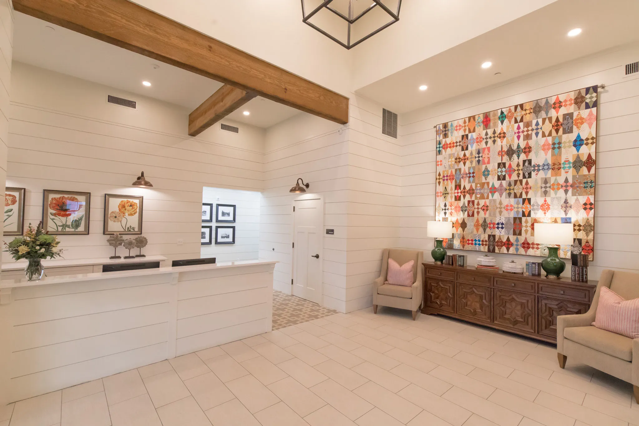 Senior living entry with an oversized patchwork quilt above a vintage sideboard beside the reception counter