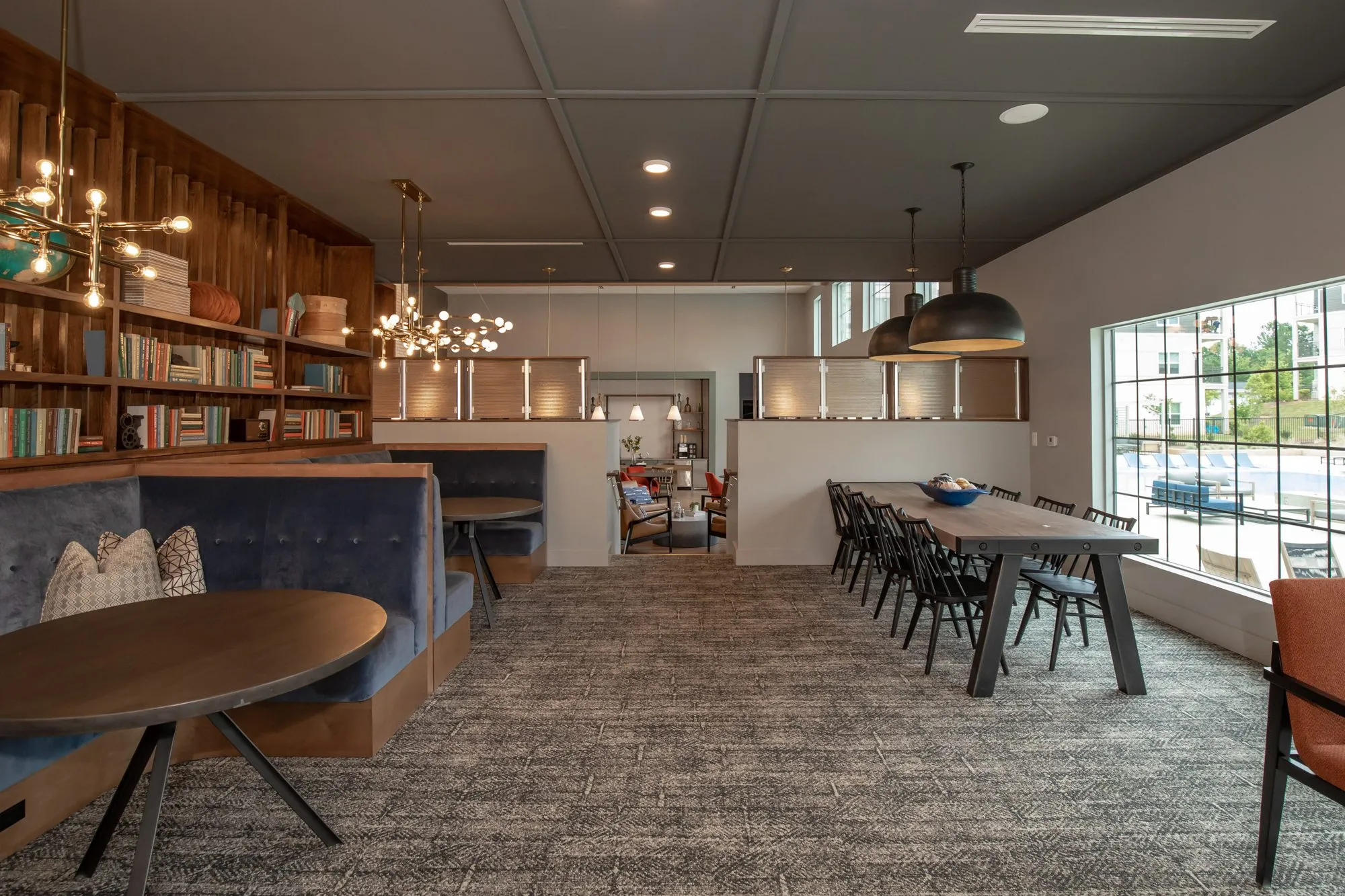 Multifamily amenity library lounge with navy banquettes and a communal table, interior design by Banko Design at Cove at Covington, Covington, Georgia